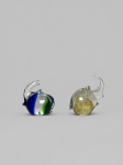 Conjunto composto por duas esculturas de elefantes em vidro artístico maciço, soprado e modelado a quente, ambas com trombas erguidas. Uma peça apresenta corpo incolor com inclusões e faixas em azul-cobalto e verde; a outra, corpo incolor com decoração interna em tons âmbar e amarelo. Sem assinaturas, etiquetas ou marcas de manufatura visíveis. Bom estado geral. Medindo: