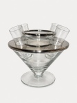 Serviço para caviar confeccionado em vidro incolor, com acabamentos em metal espessurado à prata, composto por estrutura central sobre pedestal, bandeja circular, recipiente removível para gelo, bowl interno e quatro pequenos copos cilíndricos dispostos ao redor. Apresenta marca Riva Silver Special na bandeja. Produção brasileira, segunda metade do século XX.