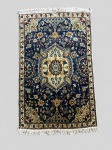 NAIN - Tapete persa confeccionado a mão em lã sobre algodão, apresentando campo azul-marinho com medalhão central marfim, ornamentado por palmetas, botehs, flores e ramagens em tons de azul, vinho, bege e verde. Cercadura clara com composição floral estilizada. Medindo 1,40 X 0,88