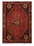 SHIRAZ - Belíssimo tapete persa de origem iraniana, região de Shiraz, confeccionado artesanalmente em lã sobre lã, apresentando amplo campo em tonalidade vermelho-terra, ornamentado por medalhão central geométrico escalonado e profusão de pequenos motivos tribais. Cantoneiras escuras com grandes elementos cruciformes e barras múltipla composta por padrões geométricos estilizados. Medindo 3,08 x 2,26.