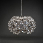 Medidas: 19 x 29 x 29 cm.Luminária pendente de design contemporâneo, estruturada por corpo circular revestido por numerosos módulos esféricos transparentes, dispostos em composição concêntrica e volumétrica. Possui difusor central translúcido, estrutura metálica, canopla circular e sistema de suspensão por cabos de aço. A sucessão de elementos transparentes amplia a difusão luminosa e produz acentuados efeitos de brilho, refração e profundidade, conferindo à peça expressiva presença visual e qualidade escultórica.