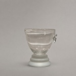 Balde de gelo individual em vidro incolor de paredes espessas, com corpo arredondado e alça anelar aplicada lateralmente. Mede 14 cm de altura por 12 cm de diâmetro. A base escalonada em vidro fosco cria contraste com a transparência do recipiente, compondo uma peça de desenho moderno e funcional para serviço de bar.