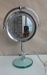 Espelho de cosmetologia dupla face sendo uma face com espelho de aumento, com lampada interna, base em vidro. Alt. 41cm