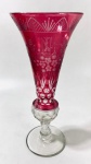 Vaso em cristal overlay francês na cor rubi, modelo corneta sobre pé trabalhado com bola facetada. Ricamente lapidado com círculos, flores e desenhos geométricos. Possui monograma "ML" lapidado. Medidas: 33 cm de altura e 14cm de bocal.
