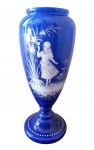 Vaso Mary Gregory em opalina azul escura  com decorção em branco em altor elevo,  representando uma menina ao lado arbusto com  flores, e base perolada. medidas 28 cm. Esse tipo de decoração diat Mary Gregory  foi realizado na Inglaterra no fim da século XIX até o inico do século XX, mais precisamente até a primeira guerra mundial, onde representava meninos e meninas em estilo romantizado da mundo em uma paisagem bucolica, esse inocência perdida com a realizada dos horrores de uma guerra ferroz. Até hoje existem varias teorias quem foi o oque foi Mary Gregory, muitos acha que ela não existiu e foi um marca de produto outro acreditam que era uma velha senhora que projetavas as crianças  que ela nunca teve em suas criaçãos.  , mas o certo é que esse tipo de decoração leva seu nome.