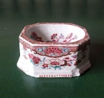 Saleiro de forma retangular com cantos chanfrados em porcelana Companhia das Índias decorada em policromia em decoração de flores, familia rosa, século XVIII, possui dois lascado na base,