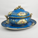 VIEUX PARIS  ATELIER DE LOCRÉ  EXPLÊNDIDA SOPEIRA COM PRESENTOIR EM PORCELANA DA MANUFATURA DE LOCRE (FUNDADA POR JEAN BAPTISTE LOCRÉ NA RUE DE FONTAINE-AU-ROI EM PARIS, 1771) E QUE POR VOLTA DE 1815, RECEBEU O TÍTULO DE FÁBRICA DE SUA ALTEZA REAL O DUQUE DE BERRY).. DE MUITO GRANDE DIMENSÃO COM FEITIO ESCALOPADO APRESENTA MARCAS DA MANUFATURA COM DUAS SETAS CRUZADAS E A LETRA D. TAMBÉM ANTIGO CACHE DE COLEÇÃO EM PAPEL NAS DUAS PEÇAS. FUNDO EM BLEU CELESTE (AZUL TURQUESA)  COM EXUBERANTES RESERVAS FLORAIS EM VIRTUOSA PINTURA MANUAL. TAMPA E PEGA DE FEITIO ROCOCÓ RECOBERTO COM OURO RICO. O PRESENTOIR SEGUE MESMO PADRÃO DECORATIVO. AS DUAS PEÇAS TEM ARREMATES EM OURO. FRANÇA, MEADOS DO  SEC. XIX. 46 CM DE COMPRIMENTO (TRAVESSA). NOTA: O termo "Velho Paris" não se refere a uma única fábrica, mas sim a um termo guarda-chuva usado por especialistas para designar a porcelana produzida por mais de 30 oficinas e manufaturas independentes que operaram na cidade de Paris entre meados do século XVIII e o final do século XIX.