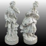 SEVRES  - POR ANTOINE-MATHIEU LIANCE (1752-1787) -  MAGNIFICO PAR DE ESCULTURAS EM PÂTE TENDRE (PASTA TENRA) DE PORCELANA APRESENTANDO CASAL EM FLERTE VESTIDOS COM TRAJES DO PERÍODO DIRETÓRIO FRANCÊS DO FINAL DO SEC. XVIII. ASSINADO AM NO INTERIOR DE MARCA DE SEVRES ADOTADAS POR ANTOINE-MATHIEU LIANCÉ (ATIVONA SEGUNDA METADE DO SEC. XVIII)): UM DOS MAIS FAMOSOS RÉPAREURS DO SÉCULO XVIII. ELE COSTUMAVA USAR VARIANTES DE SUAS INICIAIS (COMO AM OU APENAS LI) EM PEÇAS DE PORCELANA DE PASTA TENRA (PÂTE TENDRE). FRANÇA, FINAL DO SEC. XVIII. 39 CM DE ALTURA. NOTA: A pâte tendre (porcelana de pasta tenra ou mole) é considerada a era de ouro e a essência original da porcelana de Sèvres. Ela foi produzida principalmente entre a fundação da manufatura (ainda em Vincennes, por volta de 1740) até ser descontinuada oficialmente em 1804, quando a fábrica passou a focar exclusivamente na pasta dura (pâte dure). Diferente da porcelana chinesa verdadeira, a pasta tenra europeia era uma porcelana artificial. Como a França ainda não havia descoberto jazidas de caulim (o mineral essencial para a porcelana real), os artesãos criaram uma receita complexa fundindo uma mistura vítrea chamada frita (composta de areia, sal, salitre, gesso e soda) com argila branca e giz. 