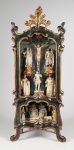 MAQUINETA OU LAPINHA - REQUINTADO ORATÓRIO DO TIPO LAPINHA ORIGINARIO DE MINAS GERAIS, ESTILO E ÉPOCA DOM JOSÉ I, DATÁVEL DE MEADOS DO SEC. XVIII. CONFECCIONADO EM MADEIRA RECORTADA E ENTALHADA APRESENTANDO POLICROMIA E DOURAMENTO. INTERNAMENTE TEM POLICROMIA PREDOMINANTEMENTE EM AZUL COM EXPLENDIDAS ROSAS DE MALABAR. EXTERNAMENTEE É REMATADA EM SALMÃO, VERMELHO E AMARELO. ESTRUTURA COM DOIS NICHOS SENDO O SUPERIOR O MAIS ALONGADO QUE O INFERIOR. MOLDURA FRONTAL COM FENDA PARA RECORTE DA CERCADURA. ANTEPARO DE VIDRO. IMAGENS EM CALCITA ENTALHADA COM LEVE POLICROMIA E DOURAÇÃO COMO ERA O GOSTO DA ÉPOCA. CRUZ EM MADEIRA. O TÍTULO CRUCIS TAMBÉM EM CALCITA. ORATÓRIO DE FATURA ERUDITA! ORNAMENTAÇÃO DA TALHA COMPOSTA POR VOLUTAS, PALMETA E FRISOS DOURADOS. NO NICHO SUPERIOR CENA DE CRUCIFICAÇÃO COM CRISTO NA CRUZ, NOSSA SENHORA DA CONCEIÇÃO, SÃO JOSÉ DE BOTAS, SANTA RITA DE CÁSSIA E SÃO JOAQUIM. NO NICHO INFERIOR CENA DA NATIVIDADE, SÃO JOSÉ E MARIA, O MENINO JESUS CALIDAMENTE ADORMECIDO  NA MANJEDOURA SEGURANDO JUNTO AO PEITO A ESFERA MUNDI, PASTORES, BOI, JUMENTO E OVELHA. AS IMAGENS SÃO FRUTO DE ESCULTURA DE GRANDE ERUDIÇÃO, SENDO ARTISTICAMENTE ESCULPIDAS. MINAS GERAIS, SEC. XVIII, 55 CM DE ALTURA.NOTA: Tipicamente mineiros os oratórios denominados lapinhas geralmente apresentam dois pavimentos, a cena clássica do Calvário com a Sagrada Parentela e algum Santo de Devoção do encomendante. Embaixo geralmente uma cena de presépio COMO NO CASO DESTE. São peças elegantes bem ao gosto Dom José I e destinados a casas de proprietários abastados. Notadamente essa arte floresceu na região de Ouro preto, Mariana e Santa Luzia. De acordo com o periódico especializado A Relíquia, no bojo da arte sacra brasileira, destacam-se os oratórios, objetos de fé, testemunhos do catolicismo, pelos quais se pode recompor a trajetória de nossa civilização. Através deles acompanha-se a imersão do fenômeno barroco na vida cotidiana do Brasil colonial. O oratório representava a ligação do homem com o divino. A origem do oratório remonta à Idade Média, época em que as famílias que não podiam construir capelas, representavam-nas através de um objeto. Para Angelo Araújo o oratório "reporta-se à edícula romana, morada dos deuses lares, e desde os primórdios do cristianismo são encontrados como objeto do culto aos mártires e santos. Ao longo de dois milênios, aparecem e ressurgem em todos os territórios da cristandade, consubstanciando estilos vigentes, tendências, influências e costumes de cada região. Os oratórios chegaram ao Brasil nos primeiros navios portugueses, como protetores daqueles intrépidos navegantes. Povoaram a cena doméstica, na cidade e no campo, das cozinhas aos quartos de dormir, das varandas às salas de jantar, dos salões as senzalas.