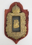 DOM PEDRO II   COLEÇÃO DR. JOSÉ RAUL DE MORAES. MUITO RARA REPRESENTAÇÃO DO IMPERADOR EM BRONZE ORMOLU APRESENTADO COMO IMPERADOR ROMANO CINGINDO TÚNICA E COROA DE LOUROS. A COROA LEMBRA MUITO AQUELA COM A QUAL  O IMPERADOR DOM PEDRO I FOI REPRESENTADO NA MOEDA CONHECIDA COMO PEÇA DA COROAÇÃO. A FIGURA DO JOVEM DOM PEDRO II COM COROA DE LOUROS E INDUMENTÁRIA ROMANA EVOCA A GRANDEZA DO IMPERIO DO BRASIL, A FIGURA DO IMPERADOR COMO AGREDADOR DA UNIDADE NACIONAL E TAMBÉM  O CARÁTER CLÁSSICO DE SUA ERUDIÇÃO. ESTE EXEMPLAR EM BRONZE SOBRE PLACA DE MADEIRA COM FEITIO DE ESCUDELA FORRADA EM TECIDO CARMESIM. EMOLDURANDO A EFÍGIE DO IMPERADOR O PAQUIFE DA BANDEIRA DO IMPERIO DO BRASIL COM RAMO DE FUMO E DE CAFÉ ATADOS PELO LAÇO NACIONAL SOB COROA IMPERIAL DE DOM PEDRO LL.   É O ÚNICO EXEMPLAR CONHECIDO E FEZ PARTE DA COLEÇÃO DO DR. JOSÉ RAUL DE MORAES UM DOS MAIS IMPORTANTES COLECIONADORES DE RELIQUIAS DO PERIODO IMPERIAL BRASILEIRO. TEM A ETIQUETA DO PREGÃO DA COLEÇÃO REALIZADO PELO LEILOEIRO ERNANI NA CIDADE DO RIO DE JANEIRO EM 1952 CUJO CATÁLOGO OFICIAL INTITULADO  IMPORTANTE LEILÃO DE OBJETOS HISTÓRICOS DO BRASIL COLONIAL E DO PRIMEIRO E SEGUNDO REINADOS: COLEÇÕES DO SNR. DR. JOSÉ RAUL DE MORAES TORNOU-SE UM DOCUMENTO CLÁSSICO DE CATALOGAÇÃO. ESSE EVENTO FOCOU EM PEÇAS DE VALOR HISTÓRICO IMENSURÁVEL. A ETIQUETA CONFIRMA A PROCEDÊNCIA DA COLEÇAO. O DR. JOSÉ RAUL DE MORAES FOI UM INFLUENTE DIPLOMATA, EMBAIXADOR E UM DOS MAIS PRESTIGIADOS COLECIONADORES DE ARTE E ANTIGUIDADES DO BRASIL DURANTE MEADOS DO SEC. XX. GRAÇAS A SUA DESTACADA CARREIRA DIPLOMÁTICA E TRANSITO INTERNACIONAL  ELE CONSEGUIU REUNIR UM DOS ACERVOS HISTOIRICOS PRIVADOS MAIS REFINADOS E VALIOSOS DO PAÍS. BRASIL, DEC. 1850. 29 CM DE ALTURA. NOTA:  Atuando como Embaixador do Brasil, José Raul de Moraes viveu em uma época em que a diplomacia brasileira (então sediada no Rio de Janeiro) era profundamente ligada à alta cultura, ao mecenato e à preservação histórica. Sua grande paixão era a história material do Brasil. Ele concentrou seus esforços em resgatar peças raras do Brasil Colonial, além do Primeiro e Segundo Reinados. O Dr. José Raul tinha um olhar cirúrgico para a prataria de lei, moedas antigas, documentos de Estado, louças brasonadas da nobreza e mobiliário imperial em jacarandá. Ele não era apenas um acumulador de objetos, mas um intelectual do colecionismo. Suas peças eram rigorosamente catalogadas e serviam como base para o estudo das artes decorativas no Brasil. O nome do Dr. José Raul de Moraes tornou-se uma lenda no mercado de arte após o seu falecimento. Sua viúva organizou a dispersão desse patrimônio por meio de leilões históricos icônicos conduzidos por pregões tradicionais (como o do leiloeiro Affonso Nunes no Rio de Janeiro).Até hoje, quando uma peça aparece no mercado com a procedência descrita como "Ex-Coleção Dr. José Raul de Moraes", ela ganha um status imediato de autenticidade e valorização máxima, pois atesta que o objeto pertenceu a uma das mentes mais refinadas do colecionismo nacional.