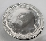 ESCRAVO DE GANHO OU MULATO DE CAPOTE RICA SALVA  BILHETEIRA EM PRATA DE LEI ESTILO DONA MARIA I BATIDA E CINZELADA. BORDA DECORADA COM PEROLADOS. ABA COM LINDAS FLORES RELEVADAS. CENTRO TEM DECORAÇÃO CARACTERÍSTICA DA PRODUÇÃO DO PRIMEIRO QUARTEL DO SEC. XIX REALIZADA PELOS ARTIFICES DENOMINADOS MULATOS DE CAPOTE. QUE ERAM ESCRAVOS DE GANHO OU ESCRAVOS LIBERTOS QUE NA SOCIEDADE BRASILEIRA ASSUMIRAM OFÍCIOS ESPECIALIZADOS NOTADAMENTE OS DE ARTÍFICES MANUAIS COMO MARCENEIROS, OURIVES, VENDEDEORES AMBULANTES E PEDREIROS. DELICADA GUIRLANDA COM LAURÉU NA BASE. SUCEDENDO A BORDA UM BARRADO COM GODRONS CONFERINDO AO CENTRO DO PLANO UM FEITIO FLORAL. A SEGUIR UMA GUIRLANDA DONA MARIA I FORMADA DE FLORES E RAMAGENS. O CENTRO TEM RESERVA COM A MARCA REGISTRADA DA MÃO DE ARTÍFICE SERVIL : PINHEIROS EM UM CAMPO. A PRÓPRIA RESERVA É EMULDURADA POR UMA GUIRLANDA.  ASSENTE SOBRE TRÊS  ELEGANTES PÉS CURVOS DECORADOS  COM CAPRICHADAS GODRONS. O TRABALHO DE ELEVADO RIGOR ARTÍSTICO REVELA TRATAR-SE DE OFICIAL EXPERIENTE E COM APURADA TÉCNICA. A SOLUÇÃO DO ARTÍFICE PARA ESTA PEÇA DE APARATO, UMA BILHETEIRA APRESENTADA PELOS CRIADOS NAS SALAS DAS CASAS SENHORIAS DENOTA A NOÇÃO DE ELEGÂNCIA  E NOBREZA ALÉM DA DELICADEZA DO TRABALHO QUE MIMETISA UMA FLOR.   NA PAGINA 177 DO LIVRO O OFÍCIO DA PRATA NO BRASIL DE HUMBERTO FRANCESCHI O AUTOR DESCREVE COM PROPRIEDADE A PRODUÇÃO E O OFÍCIO DOS MULATOS DE CAPOTE. QUE EM SUA MAIORIA NÃO ESTAVAM PRESOS A ENSINAMENTOS ACADÊMICOS, DESENVOLVERAM UMA GAMA DE TRABALHO QUE OS LEVOU A PRODUZIR TANTO FORMAS SIMPLES E PURAS QUANTO SOLUÇÕES ENGENHOSAS PARA ARREMATE DE PEÇAS DE PADRÃO ERUDITO.  FORAM REGISTRADOS EM NOSSA HISTÓRIA INÚMEROS  E INTERESSANTES RELATOS DE VIAJANTES ESTRANGEIROS QUE VISITARAM O BRASIL NO SEC. XII SOBRE O OFÍCIO DOS ESCRAVOS DE GANHO QUE EM MEADOS DO SEC. XIX. REGISTROS HISTÓRICOS VEVELAM QUE ESSE GRUPO CONSTITUIA NO RIO DE JANEIRO A A MAIORIA ABSOLUTA DA POPULAÇÃO ESCRAVA URBANA E FORMAVAM O CORAÇÃO LOGÍSTICO DA CIDADE ESTIMA-SE QUE EM MEADOS DO SECULO ERAM CERCA DE 50.000 EMPREGADOS NOS DIVERSOS OFÍCIOS. OS RELATOS E DESENHOS DE DEBRET SOBRE ESTA FACETA DA ESCRAVIDÃO SÃO MINUCIOSOS E PRECIOSOS PARA CONSTRUÇÃO DO CENÁRIO. FINALMENTE RESSALTAMOS A CONTRIBUIÇÃO DO AÇORIANO CHRISTIANO JUNIOR (1832  1902). CHRISTIANO DEDICOU-SE AOS RETRATOS DE ESTÚDIO E TORNOU-SE FAMOSO POR SEUS REGISTROS DE TIPOS NEGROS, TENDO REALIZADO IMAGENS EXCLUSIVAMENTE DE ESCRAVOS, VENDIDAS, EM GERAL, NO FORMATO DE CARTES DE VISITE. ERAM GERALMENTE VENDIDAS PARA ESTRANGEIROS QUE VOLTAVAM À EUROPA. SEU OLHAR REGISTROU INÚMEROS ESCRAVOS EM SEUS OFÍCIOS, PRINCIPALMENTE OS VENDEDORES. A TÍTULO DE INFORMAÇÃO ACRESCENTAREMOS NOS CRÉDITOS EXTRAS DESSE LOTE UM DESSES RAROS REGISTROS DO FOTOGRAFO.    BRASIL, PRIMEIRO QUARTEL DO SEC. XIX. 19 CM DE DIAMETRONOTA: As classes ou corporações de ofícios, remanescentes da idade média, suprimidas no Brasil durante o período colonial floresceram no império nascente após a independência. As ordenações do reino vedavam o oficio dos oficiais mecânicos para os infames pela raça ou por crimes. judeus mouros cristãos novos, degradados ciganos mulatos livres chamados mulatos de capote. Os ofícios eram embandeirados: pedreiros, carpinteiros de casas, canteiros, marceneiros e ladrilhadores, pertenciam a irmandade de São José. Os ourives eram da irmandade de santo Elói. Qualquer um que exercesse a profissão fora dessas agremiações exercia de forma ilegal e marginal. Logo após a independência os ofícios foram estimulados e os mulatos de capote formaram uma casta de artífices que atendiam as necessidades da sociedade e uma nova nobreza nacional. Ainda antes dos negros escravos na Bahia começarem a se organizar em irmandades. No Rio de Janeiro os pardos livres que podiam vestir-se como brancos e por isso eram chamados de "mulatos de capote" que obtiveram dos frades beneditinos o direito de cultuar seu patrono São Brás reunidos em confraria própria. Os escravos de ganho, no contexto do Brasil colonial e do Império, eram escravos obrigados pelos seus senhores a realizar algum tipo de trabalho nas ruas, levando para casa ao fim do dia uma soma de dinheiro previamente estipulada. Foi relativamente comum este tipo de escravo conseguir formar um pecúlio, que empregava na compra de sua liberdade, pagando ao senhor por sua alforria. Embora conhecida desde o século XVII nas áreas urbanas, na época do Império a prática foi mais controlada pelo estado, que concedia licença aos proprietários para o seu uso. As principais atividades a que se dedicavam eram as de carregadores, doceiras e pequenos consertos, embora alguns senhores induzissem as escravas à prostituição, o que era proibido por lei. Esses escravos, apesar de que podiam ser terrivelmente punidos se não arrecadassem os valores exigidos pelos seus senhores, tinham certas vantagens sobre os outros tipos de escravos, isso porque tinham maior mobilidade, fazendo com que tivessem mais possibilidades de circulação do que os escravos das áreas rurais e mineradoras. A ourivesaria foi o ofício que concentrou o maior número de oficiais de origem negra. Os conhecimentos trazidos do continente africano, aliados à alta demanda por joias e adornos, tornou lucrativo o aluguel de escravos oficiais de ourivesaria. As joias crioulas que ornamentavam os pulsos, colos e orelhas das negras das irmandades baianas e mineiras atestam a presença do artífice negro nas corporações de ourives. Entre os escravos  e os livres despossuídos, durante o século XIX, o termo ganho expressava a luta diária pela própria sobrevivência e a de seus familiares. ESCRAVO DE GANHO OU MULATO DE CAPOTE LINDO CASTIÇAL EM PRATA DE LEI BATIDA E CINZELADA. BORDA DECORADA COM PEROLADOS. BASE FACETADA TEM DECORAÇÃO CARACTERÍSTICA DA PRODUÇÃO DO PRIMEIRO QUARTEL DO SEC. XIX REALIZADA PELOS ARTIFICES DENOMINADOS MULATOS DE CAPOTE, DELICADA GUIRLANDA DE FLORES, BOTÕES FLORAIS E RAMAGENS. CENTRO TEM RESERVA COM TRÊS PINHEIROS E CERCA. MULATOS DE CAPOTE ERAM ESCRAVOS DE GANHO OU ESCRAVOS LIBERTOS QUE NA SOCIEDADE BRASILEIRA ASSUMIRAM OFÍCIOS ESPECIALIZADOS NOTADAMENTE OS DE ARTÍFICES MANUAIS COMO MARCENEIROS, OURIVES E PEDREIROS. O TRABALHO DE ELEVADO RIGOR ARTÍSTICO REVELA TRATAR-SE DE OFICIAL EXPERIENTE E COM APURADA TÉCNICA. NA PAGINA 177 DO LIVRO O OFÍCIO DA PRATA NO BRASIL DE HUMBERTO FRANCESCHI O AUTOR DESCREVE COM PROPRIEDADE A PRODUÇÃO E O OFÍCIO DOS MULATOS DE CAPOTE. QUE EM SUA MAIORIA NÃO ESTAVAM PRESOS A ENSINAMENTOS ACADÊMICOS, DESENVOLVERAM UMA GAMA DE TRABALHO QUE OS LEVOU A PRODUZIR TANTO FORMAS SIMPLES E PURAS QUANTO SOLUÇÕES ENGENHOSAS PARA ARREMATE DE PEÇAS DE PADRÃO ERUDITO. BRASIL, PRIMEIRO QUARTEL DO SEC. XIX. 16 CM DE ALTURA. 278 GNOTA: As classes ou corporações de ofícios, remanescentes da idade média, suprimidas no Brasil durante o período colonial floresceram no império nascente após a independência. As ordenações do reino vedavam o oficio dos oficiais mecânicos para os infames pela raça ou por crimes. judeus mouros cristãos novos, degradados ciganos mulatos livres chamados mulatos de capote. Os ofícios eram embandeirados: pedreiros, carpinteiros de casas, canteiros, marceneiros e ladrilhadores, pertenciam a irmandade de São José. Os ourives eram da irmandade de santo Elói. Qualquer um que exercesse a profissão fora dessas agremiações exercia de forma ilegal e marginal. Logo após a independência os ofícios foram estimulados e os mulatos de capote formaram uma casta de artífices que atendiam as necessidades da sociedade e uma nova nobreza nacional. Ainda antes dos negros escravos na Bahia começarem a se organizar em irmandades. No Rio de Janeiro os pardos livres que podiam vestir-se como brancos e por isso eram chamados de "mulatos de capote" que obtiveram dos frades beneditinos o direito de cultuar seu patrono São Brás reunidos em confraria própria. Os escravos de ganho, no contexto do Brasil colonial e do Império, eram escravos obrigados pelos seus senhores a realizar algum tipo de trabalho nas ruas, levando para casa ao fim do dia uma soma de dinheiro previamente estipulada. Foi relativamente comum este tipo de escravo conseguir formar um pecúlio, que empregava na compra de sua liberdade, pagando ao senhor por sua alforria. Embora conhecida desde o século XVII nas áreas urbanas, na época do Império a prática foi mais controlada pelo estado, que concedia licença aos proprietários para o seu uso. As principais atividades a que se dedicavam eram as de carregadores, doceiras e pequenos consertos, embora alguns senhores induzissem as escravas à prostituição, o que era proibido por lei. Esses escravos, apesar de que podiam ser terrivelmente punidos se não arrecadassem os valores exigidos pelos seus senhores, tinham certas vantagens sobre os outros tipos de escravos, isso porque tinham maior mobilidade, fazendo com que tivessem mais possibilidades de circulação do que os escravos das áreas rurais e mineradoras. A ourivesaria foi o ofício que concentrou o maior número de oficiais de origem negra. Os conhecimentos trazidos do continente africano, aliados à alta demanda por joias e adornos, tornou lucrativo o aluguel de escravos oficiais de ourivesaria. As joias crioulas que ornamentavam os pulsos, colos e orelhas das negras das irmandades baianas e mineiras atestam a presença do artífice negro nas corporações de ourives.