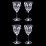 BACCARAT MALMAISON VARIANTE DO MODELO HARCOURT  QUATRO MAGNIFICAS TAÇAS PARA VINHO TINTO DO PRESTIGIADO MODELO MALMAISON UMA ELEGANTE VARIANTE DO HARCOURT QUE SURGIU NO CATÁLOGO DE 1910 DA MANUFATURA. AS TAÇAS BACCARAT MALMAISON DESTACAM-SE PELO EQUILÍBRIO ENTRE A IMPONÊNCIA DO CRISTAL LAPIDADO À MÃO E A LEVEZA DE SUAS LINHAS ESTRUTURAIS. ELAS TRAZEM UMA ESTÉTICA SÓBRIA E ARISTOCRÁTICA, TÍPICA DO ESTILO IMPÉRIO FRANCÊS. O BOJO (PARTE SUPERIOR): É ROBUSTO, PESADO E APRESENTA A FAMOSA LAPIDAÇÃO EM SEIS GOMOS OU FACETAS PLANAS E LARGAS (EXATAMENTE IGUAL AO MODELO HARCOURT). ESSAS FACETAS VERTICAIS FUNCIONAM COMO PRISMAS: QUANDO A LUZ INCIDE NO CRISTAL PURO, ELA É REFRATADA DE FORMA INTENSA, CRIANDO UM BRILHO GEOMÉTRICO MUITO CARACTERÍSTICO.  A HASTE (A PERNA DA TAÇA): AO CONTRÁRIO DA HARCOURT (QUE É CHEIA DE NÓS E ANÉIS), A HASTE DA MALMAISON É COMPLETAMENTE RETA, LISA E CILÍNDRICA. ELA NÃO POSSUI DETALHES ORNAMENTAIS, O QUE CONFERE À PEÇA UM VISUAL MUITO MAIS LIMPO, MODERNO E ANATÔMICO NA HORA DE SEGURAR. A BASE (O PÉ): TERMINA EM UM FORMATO SEXTAVADO COMO O CLÁSSICO MODELO HARCOURT, PLANO E LISO, OFERECENDO EXCELENTE ESTABILIDADE. FRANÇA,SEC XX. 18 X 8,5 CMNOTA: Baccarat Malmaison é uma famosa linha de cristal de luxo da marca francesa Baccarat, lançada por volta de 1910. Ela se destaca pelos cortes geométricos profundos e largos. A linha inclui taças, garrafas licoreiras e vasos. Peças antigas são muito raras e valiosas no mercado de colecionadores. O nome Malmaison é uma referência direta ao Château de Malmaison, o famoso palácio nos arredores de Paris que foi a residência privada de Napoleão Bonaparte e da Imperatriz Joséphine. O design da peça foi desenhado para evocar a estética do Estilo Império francês, que ditava a moda na era napoleônica: linhas simétricas, sóbrias, mas imponentes. A maior curiosidade técnica do Malmaison é sua anatomia. Se você colocar o bojo (a parte onde fica o líquido) de uma taça Harcourt e de uma Malmaison lado a lado, verá que a lapidação é praticamente idêntica: seis facetas planas e largas, cortadas diretamente no cristal maciço. A diferença crucial que define o charme da Malmaison está na haste. Harcourt: Tem uma haste robusta, cheia de anéis chanfrados e um pé hexagonal.  Malmaison:Simplifica o design com uma haste completamente reta, lisa e facetada. É a escolha perfeita para quem ama o reflexo de luz do Harcourt, mas prefere uma pegada mais alongada e sofisticada visualmente na mesa.