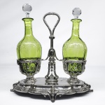 BACCARAT   SERVITEUR À LIQUEUR COMPOSTO POR DUAS LICOREIRAS E UM MAGNIFICO SUPORTE EM PRATA DE LEI CONTRASTE CABEÇA DE MERCÚRIO. A ESTRUTURA EM PRATA DE LEI É ELEGANTE APRESENTA DOIS BOJOS PARA ACOMODAR AS GARRAFAS E DOIS ANEIS CHAMADOS PORTE-BOUCHONS PARA MANTER AS ROLHAS QUANDO A BEBIDA ESTIVER SENDO SERVIDA. A BASE FORMANDO PLATEAU TEM DECORAÇÃO EM CROISE  COM PÉS CAPRICHOSAMENTE CINZELADOS COM  FEITIO DE FOLHAS. AS GARRAFAS EM CRISTAL DE URALINA SÃO ARTISTICMANETE LAPIDADAS COM FLORES E RAMAGENS. GARGALO FACETADO E TAMPA LAPIDADA EM DIAMANTE.  SÍMBOLO DE STATUS NO SÉCULO XIX, ESTA ALFAIA DE SERVIÇO TEVE SEU AUGE DURANTE OS PERÍODOS CHARLES X E NAPOLEÃO III NA FRANÇA. ERA PEÇA CENTRAL NOS SALÕES DA ALTA BURGUESIA PARA IMPRESSIONAR CONVIDADOS APÓS O JANTAR FRANÇA, FINAL DO SEC. XIX. 27 CM DE ALTURA A BASE EM PRATA PESA 375 G