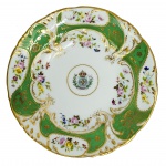 DOM PEDRO I E DOM PEDRO II - SERVIÇO DE GALA FORMIDÁVEL PRATO EM PORCELANA DO SERVIÇO DE GALA, PRIMEIRO SERVIÇO IMPERIAL BRASILEIRO; ABA VERDE ENTRE FILETES DOURADOS E QUATRO RESERVAS COM FLORES EM POLICROMIA; NO CENTRO O BRASÃO IMPERIAL CINCUNDADO POR FRISO DOURADO; NO REVERSO MARCA DO IMPORTADOR B. WALLERSTEIN E CO - A PARIS / RUA DO OUVIDOR 70 - RIO DE JANEIRO. PEÇA DO MESMO SERVIÇO REPRODUZIDA NA PÁGINA 209 DO LIVRO LOUÇA DA ARISTOCRACIA NO BRASIL, POR JENNY DREYFUS. EXISTEM PARA ESSE SERVIÇO DUAS MARCAS DE ENCOMENDANTES O QUE FAZ CONCLUIR QUE ESTE ERA UTILIZADO PELA FAMÍLIA IMPERIAL DESDE O PRIMEIRO REINADO COM ENCOMENDA PARA REPOSIÇÃO NO SEGUNDO REINADO. PORTANTO O SERVIÇO FOI EMPREGADO POR DOM PEDRO I E DOM PEDRO II. ESSE PRATO OFERTADO NO LOTE EM TELA FOI ENCOMENDA DO IMPERADOR DOM PEDRO II EM MEADOS DO SEC. XIX. FRANÇA, dec. 1850 XIX. 22,5 CM DE DIÂMETRONOTA: O cotidiano das refeições no Paço de São Cristóvão, residência oficial da família imperial no Rio de Janeiro, era regido por uma rotina surpreendentemente rígida, simples e, por vezes, cômica para quem olhava de fora. Um dos registros mais famosos sobre a dinâmica dessas refeições envolve a lendária pressa de Dom Pedro II à mesa e foi eternizado pelo folclorista Luís da Câmara Cascudo:  O imperador acordava religiosamente às 5h da manhã. Por conta disso, o almoço no palácio era servido extraordinariamente cedo, por volta das 9h da manhã. Dom Pedro II detestava perder tempo comendo; suas refeições prediletas resumiam-se a pratos rápidos como arroz, feijão ou sua inseparável canja de galinha, engolida em poucos minutos.  O protocolo da corte exigia que, assim que o monarca terminasse de comer e se levantasse, a refeição estava oficialmente encerrada para todos. Como o imperador devorava seu prato em velocidade recorde, os convidados, diplomatas e a própria guarda imperial frequentemente saíam da mesa com fome crônica.  O jantar noturno no Paço de São Cristóvão ocorria rigorosamente às 17h (cinco da tarde). O cardápio misturava a simplicidade mineira com a tradição francesa e o protocolo era extremamente rígido:  Consistia em canja de galinha, arroz com carne-seca ou lombinho de porco, feijão e couve.  Doces de compota portugueses e, curiosamente, bananas, que Dom Pedro II adorava. O imperador raramente bebia álcool, preferindo água pura ou uma única taça de vinho de Borgonha. Ninguém podia falar antes do imperador, e os criados serviam os pratos usando luvas de pelica brancas.  A refeição durava exatos 30 minutos e terminava assim que o monarca largava os talheres. A culinária do Brasil Império mesclava a sofisticação da gastronomia francesa com ingredientes brasileiros e receitas tradicionais portuguesas, registradas no icônico livro O Cozinheiro Imperial (1839).Abaixo esta a  receita célebre da canja de DOM PEDRO II.   Canja de Galinha à Moda do Imperador (O prato favorito de Dom Pedro II): A "Sopa do Imperador" era consumida diariamente. No Rio Imperial, confeitarias costumavam inovar a versão lusa adicionando um toque de presunto defumado ao caldo. Ingredientes: 1 frango inteiro cortado em pedaços (ou galinha caipira); 1 xícara de arroz branco; 2 cenouras em cubos; 50g de presunto cru ou bacon defumado em cubos bem pequenos; 1 cebola picada; 2 dentes de alho; hortelã fresca; sal e pimenta-do-reino. Preparo: Doure a cebola, o alho e o presunto picado em um fio de azeite. Adicione os pedaços de frango e sele bem. Cubra com bastante água e cozinhe em fogo lento até a carne quase soltar dos ossos. Retire o frango, desfie a carne e descarte os ossos e o excesso de gordura. Volte o frango ao caldo, junte as cenouras e o arroz, cozinhando até que fiquem macios. Sirva bem quente com folhas de hortelã fresca por cima.