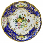 DOM PEDRO II SERVIÇO DE CAÇA PRATO EM PORCELANA FRANCESA, ABA AZUL ROYAL E DOURADO; QUATRO RESERVAS, DUAS A DUAS, COM PÁSSAROS E FLORES; CALDEIRA COM RAMO DE FLORES EM POLICROMIA E ARABESCOS DOURADOS. ESSE APARELHO FOI OFERECIDO A DOM PEDRO II PELO IMPERADOR DA FRANÇA NAPOLEÃO III ENTRE 1852 E 1870. O ANUÁRIO DO MUSEU IMPERIAL BRASILEIRO PUBLICADO EM 1942 , VOLUME TRÊS, PAG 147 TRAZ SOBRE ESSE SERVIÇO AS SEGUINTES INFORMAÇÕES: SERVIÇO COM BORDA DECORADA A AZUL E OURO, COM FLORES E FAISÕES NOS OVAIS (RESERVAS) E FLORES NO CENTRO, NÃO BRASONADO. APARELHO CONHECIDO COMO SERVIÇO DE CAÇA, OFERECIDO A D. PEDRO II POR NAPOLEÃO III. APREGOADO NO LOTE N. 558 DO LEILÃO DE SÃO CRISTÓVÃO. REPRODUZIDO À PÁGINA 211 DO LIVRO "LOUÇA DA ARISTOCRACIA NO BRASIL", POR JENNY DREYFUS. FRANÇA, SÉC. XIX. 23 CM DE DIÂMETRO. NOTA: REPRODUZO AQUI O CONTEÚDO DAS PÁGINAS 143 E 144 DO ANUÁRIO DO MUSEU IMPERIAL BRASILEIRO PUBLICADO EM 1942 SOB O TÍTULO DE PORCELANAS DA CASA DE BRAGANÇA ONDE SE DISCORRE SOBRE REMINISCÊNCIAS DE PERSONAGENS VIVOS HÁ ÉPOCA QUE ERAM FREQUENTADORES DO PAÇO IMPERIAL NA ÉPOCA DE DOM PEDRO II: Ouvir o amigo Virgílio, que ainda está vivo e são, com a memória bem fresca, no relato de episódios a que assistiu na sua mocidade, no acidentado e trabalhoso campo do seu árduo mister, é o mesmo que folhear um livro de impressões, de comum decoradas com tintas vivas, as próprias tintas de que é tão rica sua paleta de pintor. Foi ele, ao que se viu, um dos martelos desse leilão insigne, quem primeiro lançou aos ares da cidade, entre as árvores robustas da velha quinta imperial, o pregão melancólico das grandes coisas históricas, o desbarato inicial do regime que se impunha. Quanto dão por isto? E por aquilo? gritava o arauto, erguendo sobre as cabeças atônitas os mais caros e prezados ornamentos do Brasil monárquico. E os candidatos acorriam, nervosos, febricitantes. Disputavam as peças propaladas com esse afã tumultuário de casa de jogo que tem todos os leilões. Muitos, aterrorizados, lançavam medrosamente as ofertas ou as mandavam lançar não fosse estar por ali, detrás daqueles reposteiros armoriados, algum cérbero republicano. Outros, jocosos, em geral aderentes de última fornada, como emplastros caseiros que se agarram a qualquer protuberância, faziam troça, metiam a ridículo a coisa apregoada, achincalhavam o palácio, o imperador, os príncipes, a monarquia, sem saber, na sua alta ignorância, que zombavam da própria história pátria. Virgílio, braço direito do velho J. Dias, ia cumprindo, indiferente, o seu dever. Agora, um objeto de sensação. Um piano de cauda, todo em jacarandá, com esculturas e filetes dourados, da melhor fábrica inglesa. Quanto vale, senhores? Foi da princesa Isabel. Nele tocou o grande Gottschalk. E para garantir as vozes do instrumento, ele mesmo em pessoa larga o martelo inseparável, assenta-se à banqueta estofada e executa com graça e petulância um trecho do seu repertório. Sucesso! Os assistentes aplaudem. Abraçam o concertista improvisado. E o piano famoso alcança a soma exorbitante de dois contos de réis! Por fim, o leilão termina. Durara vários dias. Fora o assunto de todas as conversas, no Parlamento, nos cafés, nos clubes, nos lares, nas ruas da cidade. Fiel ao trono deposto, a velha-guarda, que comparecia diariamente àqueles desoladores espetáculos, comprava o que podia, de rosto grave, compungido, ufana de ainda poder acautelar alguma coisa que houvesse sido honrada com o carinho paternal de Suas Majestades. Por fim, todo mundo dispersa. Vai-se tornando deserto o parque antigo de Elias Lopes. Deserto o casarão arquejante de tanta passada inútil pelos seus salões dourados, pelos seus longos e sombrios corredores. Deserto o jardim bonançoso onde os pássaros chilreiam, sob as ramadas hospitaleiras, por sobre as águas livres e cantantes. Daqui, dali, montando guarda aos destroços da monarquia, um ou outro soldado, a sentinela sonolenta daqueles pousos abandonados. Ao cabo do dramático episódio, já cerrando as portas, Virgílio, certa manhã dessa tristonha primavera, desce ao fundo do paço, pára em frente de um tapume de madeira, desses escuros vãos de escada onde os jardineiros costumam recolher as ferramentas. Espia por uma fresta. Vê lá dentro alguma coisa que brilha. Força a entrada, e dá com os olhos em quatro enormes caixas de Flandres. Consulta as suas notas. Corre os lotes desprezados por sua insignificância entre panelas velhas, cacarecos e trastes imprestáveis. Lá está: quatro latas de folha, avaliadas a seiscentos réis. O lote inteiro, dois mil e quatrocentos. Mas afinal, que será? Só isso teriam dado pelas caixas. O fato é que elas estavam pesadas. Conteriam alguma coisa útil, quem sabe, alguma coisa de valor? Assim fechadas, lacradas com os sinetes do Império... Não. Vamos a ver que diabo se intromete nelas? E abre uma caixa: salta um berço de criança. E que berço, santo Deus! Que maravilha de arte, com as suas esculturas de pau santo, os seus anjinhos esvoaçantes, as suas bolas de marfim legítimo! Que se abra a outra lata. Outro berço. Igualzinho ao primeiro, com o mesmo luxo, o mesmo estilo, a mesma graciosidade. E assim o terceiro e o quarto. Aturdido, Virgílio chama um velho servidor do paço, que por ali ainda se detinha, a capinar distraidamente, mero pretexto de matar saudades. Que é isto, meu amigo? Isto, seu moço? O sinhô antão num sabe o que é isso? São os berços dos príncipes! Muito esta mão véia cansada embalô eles... E eram mesmo. Os bercinhos gentis dos herdeiros do trono. Ali jogados como inutilidades, os casulos de ouro e seda que tanto sonho adormentaram. Cuvier, com o auxílio de um osso, era capaz de reconstituir todo o complexo arcabouço de um megatério. Pois ficou no Brasil, dadas as proporções estéticas, o osso de Cuvier na reconstituição fiel das porcelanas da casa de Bragança. É a nota sentimental de todo este incompleto e descorado estudo. À força de passar de mão em mão, das mais rudes às mais aristocráticas, em quase um século de vida palaciana, as louças dos três reinados, embora aparecendo nas bem fornecidas ucharias em quantidades apreciáveis, dando muito que fazer às numerosas criadagens do Paço da Cidade, da Boa Vista, de Santa Cruz e de Petrópolis, foram naturalmente se partindo, se aglomerando num montão de estilhaços, não se fizessem da matéria frágil muita vez santificada pelo sopro do gênio, cacos desgraciosos o que era dantes refinamento e esplendor. Mas, como acontece aos fragmentos de um espelho, que continuam a refletir inteiramente a imagem como se fora o próprio espelho, integral e perfeito, essas partículas informes dos Ming, dos Saxe, dos Sèvres, dos Limoges, dos Haviland, dos Viena dÁustria, dos Bourg-la-Reine e dos Capo di Monte, conquanto reduzidos à expressão mais simples, representavam nitidamente a sua origem, o seu valor intrínseco, o seu rútilo brasão artístico. E que destino tiveram esses cacos? Sumiram-se, no roldão dos tempos, de envolta a tanta coisa, a tanta raridade extraviada? Não. Pela graça divina, foram salvos. Houve mão de mulher, mão delicada de donzela patrícia, que os recolheu com usura e emoção, e os preservou da confusão e do esquecimento, até que, achandoos em volume suficiente, lançou-os ela em pessoa, como um suave devaneio de descuidados quinze anos, a uma mimosa missão que resultou em paciente obra-prima. Era cheio de gosto e de ternura, num labor incessante de muitos dias, o arranjo decorativo de um pequenino jardim que logo se apelidou o Jardim da Princesa. Que é feito de Isabel? perguntava a imperatriz à sua dama de serviço. Senhora, não a vejo há muitas horas. Já a procurei na sala de jantar, no quarto da princesa Leopoldina, no seu salão de música, na sua sala de costura. Não está. Sua Majestade o Imperador já me fez a mesma pergunta. A jovem estava fora, num recanto do parque, por detrás do casarão da quinta, entretida no seu silencioso mister. Isabel de Bragança, com a mesma graça serena com que mais tarde na agonia do Império, empunharia o cálamo sublime para livrar do cativeiro uma raça, com os cabelos de ouro ao grande sol do parque, constituía o seu refúgio, iluminava-o a coloridos embrechados desses sonoros pedaços das mais antigas porcelanas, engastados nos bancos, nos muros frios e limosos, nos parapeitos recobertos de hera, onde quer um olhar, admirado pudesse contemplar esse trabalho singelo, esse divertimento de criança em que, a cada manhã nascente, o sol colaborava em pinceladas de ouro. O Jardim da Princesa, é, pois, um índice vivente, um resumo ilustrado de quanta louçaria bragantina resplendeu e serviu no Brasil, e enfim se desmantelou após o rumor festivo dos grandes ágapes nacionais ou o simples tocar de taças nos tranqüilos jantares domésticos com os mesmos temas de conversa da vida íntima da mais pacata família burguesa. Princesinha de histórias encantadas lindo retrato de boa fada amiga na moldura de cabiuna dos anjos da Abolição a doce. herdeira de um trono, com a régia mão redentora, entretecia a sorrir os sagrados painéis adolescentes dos seus sonhos de virgem, como qualquer mulher da sua idade. Aí fica, em pálido resumo, o que me foi dado recolher sobre o acervo cem vezes maravilhoso das louças da Casa de Bragança. Bem haja a fundação desses museus que as atalaiam e preservam do desmantelo e do olvido. Bem haja a idéia do levantamento desses egrégios bastiões de arte e história a quem devemos todos, obreiros diligentes do pensamento e da pena, dar muito do nosso esforço e da nossa incondicional solidariedade. Gastão Penalva.
