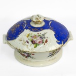 DOM PEDRO II  - MAIS TARDE PERTENCEU AO BARÃO DE ITACURUÇÁ (MANOEL MIGUEL MARTINS O GRANDE ARREMATANTE DOS LEILÕES IMPERIAIS APÓS A PROCLAMAÇÃO DA REPÚBLICA). MAGNIFICA TERRINA COM TAMPA EM PORCELANA  (TEM O PAR APREGOADO NO LOTE A SEGUIR) COM EXUBERANTE TOM EM AZUL REMATADO EM OURO COM CACHOS DE UVAS E PARRAS. PALMÁCEAS RELEVADAS COMPLETAM A DECORAÇÃO. LUXURIANTE DECORAÇÃO FLORAL EM ESMALTE. MARCAS DA CASA COMERCIAL B WALLERSTEIN & CIA IMPORTADORA DO RIO DE JANEIRO. ESSE SERVIÇO HÁ MUITO TEMPO TEM SIDO ALVO DE DISCUSSÕES SOBRE A TITULARIDADE DO ENCOMENDANTE INICIAL. ISSO PROQUE A DECORAÇÃO É IDÊNTICA AO SERVIÇO DE CAÇA DE DOM PEDRO II. ENTRETANTO EM ESTUDO RECENTE CHEGOU-SE AOS ASPECTOS QUE FAZEM REIVINDICAR AO IMPERADOR PEDRO II E SEU SERVIÇO DE CAÇA TAMBÉM ESSE SERVIÇO QUE PERTENCEU POSTERIORMENTE AO BARÃO DE ITACURAÇÁ ADQUIDIRO NO LEILÃO DOS PAÇOS IMPERIAIS. SENÃO VEJAMOS: A MARCA DO IMPORTADOR SOB A LOUÇA É DA CASA COMERCIAL B WALLERSTEIN & CIA IMPORTADORA DO RIO DE JANEIRO NAS RUA DO OUVIDOR, FORNECEDORES DA CASA IMPERIAL E IDENTICA A MARCA DA LOUÇA DO SERVIÇO DE GALA DE DOM PEDRO I. BERNANDO WALLERSTEIN ESTABELECEU-SE NA RUA DO OUVIDOR AINDA EM 1828, SOB O NOME DE WALLERSTEIN & CIA, DURANTE O PRIMEIRO IMPÉRIO APÓS DESVINCULAR-SE DA P SAISSET & CIA COM QUEM TINHA SOCIEDADE. AINDA NA DÉCADA DE 1840, QUANDO O BARÃO DE ITACURUÇÁ SEQUER TINHA NASCIDO MUDOU SUA RAZÃO SOCIAL PARA B. WALLERSTEIN E M. MASSET PORTANTO ESSA LOUÇA FOI CERTAMENTE ENCOMENDADA NA DECADA DE 1840 NUNCA PELO BARÃO DE ITACURUÇÁ QUE VEIO AO MUNDO DEPOIS QUE A IMPORTADURA ABANDONOU A MARCA SOB A BASE. O FATO DA DECORAÇÃO SER IDÊNTICA A DO SERVIÇO IMPERIAL DE CAÇA TAMBÉM REFORÇA A UNIDADE DO APARELHO. O LIVRO DA MORDOMIA DO PAÇO DE SÃO CRISTÓVÃO RELATA VÁRIAS ENCOMENDAS DE PORCELANA FEITAS A CASA DE BERNARDO WALLERSTEIN NA DECADA DE 1840: 192$500 A BERNARDO WALLTERSTEIN E CIA., POR QUINHENTOS E DEZESSEIS PRATOS DE PORCELANA FINA 5:132$736 A BERNARDO WALLERSTEIN, POR NOVE DÚZIAS E QUATRO CASAIS DE XÍCARAS DE PORCELANA FINA DOURADA 373$330: A WALLERSTEIN, LOUÇA DE PORCELANA FINA 927$000 A B. WALLERSTEIN, POR QUATRO CAIXAS COM LOUÇA DE PORCELANA FINA 4:848$000 . FINALMENTE O BARÃO DE ITACURUÇÁ COMO GRANDE ARREMATANTE DOS LEILÕES DO PAÇO APÓS A PROCLAMAÇÃO DA REPÚBLICA ADQUIRIU DENTRE OUTRAS PRECIOSIDADES TODO O SERVIÇO DE PORCELANA DO CASAMENTO DE D. PEDRO I E D. AMÉLIA DE LEUCHTEMBURG ERA UM APRECIADOR DE PORCELANAS IMPERIAIS. SEGUNDO O ANÚARIO DO MUSEU IMPERIAL DE PETRÓPÓLIS PUBLICADO EM 1944 OS CATÁLOGO DO QUARTO E SEXTO LEILÕES DO PAÇO DE SÃO CRISTÓVÃO EM 1890 TRAZEM DESCRITOS COMO LOTE 838 A SEGUINTE DESCRIÇÃO: - 1 SOBERBO SERVIÇO DE FINA PORCELANA FRANCESA, ESMALTE AZUL, OURO, E FINAS PINTURAS, COM 568 PEÇAS PARA JANTAR. ESTÁ AÍ A DESCRIÇÃO DO SERVIÇO IMPERIAL MUITO PROVAVELMENTE ARREMATADO PELO BARÃO DE ITACURUÇÁ. AINDA O LOTE 857 TRAZ A SEGUINTE DESCRIÇÃO: 857 - 1 RIQUÍSSIMO SERVIÇO DE FINÍSSIMA PORCELANA DE SÈVRES COM PRIMOROSAS PINTURAS A ESMALTE E ARMAÇÃO DE BRONZE DOURADO A FOGO, 17 PEÇAS EM VITRINE (PRESENTE DE NAPOLEÃO III À IMPERATRIZ DONA TERESA CRISTINA. ENTÃO O LOTE 857 É O APARELHO PRESENTEADO POR NAPOLEÃO III AOS IMPERADORES E NÃO O DO LOTE NUMERO 838 QUE QUASE INDUBITAVELMENTE É O SERVIÇO ADQUIRIDO PELO BARÃO DE ITACURUÇÁ. REPRODUZIDO NA PAGINA 274 DO LIVRO LOUÇA DA ARISTOCRACIA NO BRASIL DE JENNY DREYFUS E NA PAGINA 44 DO LIVRO LOUÇA HISTÓRICA MUSEU DE ARTE DA BAHIA. FRANÇA, 26 CM DE DIAMETRONOTA: Manoel Miguel Martins Barão de Itacurussá, nasceu em10 de novembro de 1831 em Sant'Ana do Itacurusá e faleceu em 01 de janeiro de 1911, filho deJoão Martins e de Gertrudes Margarida. Casou em09 de março de 1867, no Rio de Janeiro, com Jerônyma Eliza de Mesquita, Baronesa de Itacurusá nascida em02 de junho de1851 no Rio de Janeiro/RJ e batizada na Igreja de Santa Rita, e falecida em 24 de setembro de 1917, filha de Jerônymo José de Mesquita Conde de Mesquita e de Elisa Maria de Amorim. Casaram-se em 09 de março de 1867 (portanto Jerônima estava com 16 anos de idade) na Igreja de S. Francisco Xavier. Título nobiliárquico de Barão de Itacurussá outorgado , em 25 de março de 1888, a Manuel Miguel Martins era um título de origem toponímica. Ilha e povoação do Estado do Rio de Janeiro, lugar de onde era natural este titular. Foi um homem riquíssimo, proprietário de terras e capitalista do Rio de Janeiro. Sua esposa a baronesa Jerônima Elisa de Mesquita Martins, era filha do conde de Mesquita e neta do marquês de Bomfim. O Barão foi o grande comprador do Leilão do Paço Imperial, onde além de muitas preciosidades, adquiriu todo o serviço de porcelana do casamento de D. Pedro I e D. Amélia de Leuchtemburg.