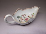 DOM JOÃO VI  - SERVIÇO DOS PAVÕES - RARA E ELEGANTE MOLHEIRA DO TIPO SAUCE BOAT EM PORCELANA CHINESA DO REINADO QIANLONG. BORDA RECORTADAS COM DECORAÇÃO EXTERNA E INTERNA EM ESMALTES. ARREMATES EM OURO. CHINA, SEGUNDA METADE DO SEC. XVIII.  23 CM DE COMPRIMENTONOTA: Dom João VI voltou a Portugal em 26 de abril de 1821, levando cerca de 4 mil pessoas na comitiva e deixando seu filho Dom Pedro I no Brasil. Essa viagem marcou o fim da permanência da corte no Rio de Janeiro após a pressão da Revolução do Porto.  Dom João VI não levou apenas os vivos; ele transportou nos navios os corpos de parentes que faleceram no Brasil, como sua mãe, a rainha Dona Maria I.  Com a partida de cerca de 4 mil nobres e funcionários, o Rio de Janeiro perdeu o posto de sede do Império Português e viveu um clima de forte instabilidade política.que culminaria com a Independência do Brasil.  SOBRE O RARO FEITIO SAUCE BOAT: A molheira em formato sauce boat (barco de molho) da Companhia das Índias é uma das peças mais fascinantes do colecionadorismo de antiguidades, unindo a utilidade aristocrática europeia à perfeição técnica da porcelana chinesa de exportação. Produzidas principalmente durante os séculos XVIII e XIX (Dinastia Qing), estas peças guardam histórias e curiosidades surpreendentes sobre o comércio global e os costumes da época.
