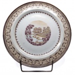 D. JOÃO VI - SERVIÇO VISTA GRANDE - FAZENDA SANTA CRUZ. LINDO PRATO  EM PORCELANA COMPANHIA DA ÍNDIAS REINADO JIAQING (1796-1820), BORDA CIRCULAR, ABA COM FRISO GEOMÉTRICO MARROM REMATADO EM DOURADO; NO CENTRO PAISAGEM CIRCULAR EM SÉPIA REPRODUZINDO RIO, VEGETAÇÃO, PERSONAGENS E MONTANHAS. REPRODUZIDO À PÁGINA 93 DO LIVRO "LOUÇA DA ARISTOCRACIA NO BRASIL" POR JENNY DREYFUS. CHINA, SÉC. XVIII. 25 CM DE DIAMETRO .NOTA: A Fazenda Imperial de Santa Cruz (ou Fazenda de Santa Cruz, Fazenda Real de Santa Cruz, ou Fazenda dos Jesuítas, ou, ainda, Fazenda Nacional de Santa Cruz ) foi uma fazenda próspera fundada em pelos padres Jesuítas nos arredores da cidade do Rio de Janeiro. Sua sede e núcleo principal corresponde hoje ao Bairro carioca de Santa Cruz. Após o Descobrimento do Brasil, com a chegada dos colonizadores portugueses à baía da Guanabara, a vasta região da baixada de Santa Cruz e montanhas vizinhas, foi doada a Cristóvão Monteiro, da Capitania de São Vicente, como recompensa aos serviços prestados durante a expedição militar que, em 1567, expulsou definitivamente os franceses da Guanabara. Ao morrer Cristóvão Monteiro, a sua esposa, dona Marquesa Ferreira, doou aos padres da Companhia de Jesus sua parte das terras. Estes religiosos, agregaram estas terras a outras sesmarias, constituíram um imenso latifúndio assinalado por uma grande cruz de madeira: a Santa Cruz. Em poucas décadas, a região compreendida entre a barra de Guaratiba, o atual município de Mangaratiba, até Vassouras, no Sul do atual Estado do Rio de Janeiro, integrava a poderosa Fazenda de Santa Cruz, a mais desenvolvida da Capitania do Rio de Janeiro nesta época, contando com milhares de escravos, cabeças de gado, e diversos tipos de cultivos, manejados com técnicas avançadas para a época. Entre as edificações, hoje com valor histórico, contam-se igrejas e um convento, ambos ricamente decorados. Uma dessas obras remanescentes é a chamada Ponte do Guandu ou Ponte dos Jesuítas. Na verdade uma represa, foi erguida em 1752, com a finalidade de regular o volume das águas das enchentes do rio Guandu. Atualmente, esse monumento permanece com a sua estrutura original quase inalterada. Outra das admiráveis iniciativas dos dirigentes da Fazenda de Santa Cruz, no plano da cultura, foi a fundação de uma Escola de Música, de uma Orquestra e de um Coral, integrados por escravos, que tocavam e cantavam nas missas e nas festividades quer na Fazenda, quer na Capital da Capitania. Considera-se, por essa razão, que Santa Cruz foi o berço da organização instrumental e coral do primeiro Conservatório de Música no Brasil. Passa pelas terras da Fazenda de Santa Cruz a trilha que no período colonial ligava a cidade de São Sebastião do Rio de Janeiro ao sertão: o Caminho dos Jesuítas, posteriormente denominado Caminho das Minas, e posteriormente ainda, Estrada Real de Santa Cruz. O seu percurso estendia-se até ao porto de Sepetiba, onde se embarcava com destino à cidade de Parati, de onde partia a antiga Estrada Real. Diante da expulsão dos Jesuítas dos domínios de Portugal e suas colônias, em 1759 por ação do Marquês de Pombal, o patrimônio da Companhia de Jesus (e a Fazenda de Santa Cruz) reverteu para a Coroa. Com o banimento dos Jesuítas do Brasil, o patrimônio da Fazenda de Santa Cruz reverteu para a Coroa, passando a se subordinar aos Vice-reis. Após um período de dificuldades administrativas, sob o governo do Vice-rei Luís de Vasconcelos e Souza, a Fazenda voltou a conhecer um período de prosperidade. No início do século XIX, com a chegada da Família Real ao Brasil (1808) e o seu estabelecimento no Rio de Janeiro, a Fazenda foi escolhida como local de veraneio. Desse modo, o antigo convento foi adaptado às funções de paço real - Palácio Real de Santa Cruz. Sentindo-se confortável na Real Fazenda de Santa Cruz, o Príncipe Regente prolongava a sua estada por vários meses, despachando, promovendo audiências públicas e recepções a partir da mesma. Nela cresceram e foram educados os príncipes D. Pedro e D. Miguel. Por iniciativa do soberano português foram trazidos da China cerca de cem homens encarregados de cultivar chá, no sítio hoje conhecido como Morro do Chá. Durante quase um século essa atividade foi produtiva e atraiu o interesse de técnicos e visitantes, tal o pioneirismo de sua implantação no Brasil. No entanto, de acordo com o jornalista Patrick Wilcken, no seu livro Império à Deriva (2010), o chá-da-índia cultivado em solo brasileiro não apresentou as mesmas características originais, sendo de qualidade inferior e de gosto amargo, o que acarretou em fracasso econômico ao contrário do café. D. João VI despediu-se de Santa Cruz em 1821, para retornar à Metrópole Portuguesa. Após o regresso de D João VI a Portugal, o Príncipe-Regente D. Pedro continuou constantemente presente em Santa Cruz, passando sua lua-de-mel com a Imperatriz Leopoldina (1818) nesta fazenda. No contexto da Independência do Brasil, antes de iniciar a história viagem da Independência, o príncipe-regente deteve-se em Santa Cruz, onde aconteceu uma reunião no dia 15 de agosto de 1822, com a presença de José Bonifácio, para estabelecer as suas bases. Ao regressar, antes de seguir até a cidade, comemorou a Independência do Brasil na Fazenda. Durante o Primeiro Reinado, o Palácio Real transformou-se em Palácio Imperial. D. Pedro I, abdicou do trono, mas os seus filhos continuaram a manter presença constante na Fazenda Imperial de Santa Cruz. Desde cedo, D. Pedro II e as princesas promoviam concorridos bailes e saraus no Palácio Imperial. Santa Cruz, por sua posição político-econômico e sobretudo estratégica (frente para o mar e fundos para os caminhos dos sertões de Minas) foi uma das primeiras localidades do País a se beneficiar com o sistema de entrega em domicílio de cartas pelo correio. Em 22 de novembro de 1842 foi inaugurada a primeira Agência fixa dos Correios do Brasil, primeira também a adotar este serviço. Dom Pedro II também instalou o primeiro telefone no Palácio Imperial de Santa Cruz, para comunicação com o Paço de São Cristóvão. Em 1878 foi inaugurada a estação de trem e no final de 1881, D. Pedro II inaugurou o Matadouro de Santa Cruz, tido como o mais moderno do mundo à época, que era servido por um ramal da estrada de ferro e abastecia de carne toda a cidade do Rio de Janeiro. Com o passar dos anos, uma série de modificações na arquitetura do prédio principal da fazenda de Santa Cruz, devido aos novos usos: Convento na era jesuítica, Palácio Real no tempo de D.João VI, Palácio Imperial com novas reformas no tempo de D. Pedro I e finalmente, no período republicano, com a construção de mais um andar, passou a aquartelar tropas do Exército. Hoje é a Sede do Batalhão Escola de Engenharia, o Batalhão Villagran Cabrita.