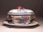 DINASTIA QING - REINADO QIANLONG  (1736-1935)  - FORMIDÁVEL SOPEIRA COM SEU PRESENTOIIR EM PORCELANA CHINESA DE EXPORTAÇÃ COM PALETA DECORATIVA YANGCAI DA FAMÍLIA ROSA. LINDAS FLORES REALÇADAS POR ESMALTES AZUIS REMATADOS EM OURO COM ESCAMAS DE PEIXE. PEGAS  LATERAIS COM FEITIO DE CABEÇAS DE JAVALI. TAMBPA COM FORMATO DE ROMÃ, UM SÍMBOLO DE PROSPERIDADE , FERTILIDADE E DESCEDÊNCIA NUMEROSA SEGUNDO A TRADIÇÃO CHINESA. O ARRANJO DE FLORES CENTRAIS E AS BORDAS DECORADAS MISTURAM A DELICADEZA ORIENTAL COM O GOSTO DA ARISTOCRACIA E NOBREZA EUROPÉIA. . o MERCADO OCIDENTAL FAZIA SUAS ENCOMENDAS TENDO EM VISTA A COMBINAÇÃO COM A DECORAÇÃO BARROCA E ROCOCÓ DOS PALÁCIOS DA ÉPOCA.. O PRESENTOIR SEXTAVADO COMO A SOPEIRA TEM NO FUNDO O ACABMAENTO UNGLAZED SEM ESMALTE QUE LHE CONFERE UMA DESEJÁVEL FINALIZAÇÃO RÚSTICA. MAGNIFICO CONJUNTO EM EXCEPCIONAL ESTADO DE CONSERVAÇÃO! CHINA, MEADOS DO SEC. XVIII. 37 CM DE COMPRIMENTO (PRESENTOIR).NOTA: Esta sopeira carrega histórias fascinantes sobre a globalização, segredos industriais e a diplomacia do século XVIII. A sopeira era considerada a joia da coroa de um serviço de mesa no século XVIII. Ela ocupava o centro absoluto da mesa e servia como o maior símbolo de status e riqueza do anfitrião. Encomendar um conjunto completo com sopeira e presentoir (o prato debaixo) à Companhia das Índias custava uma fortuna equivalente a um pequeno palácio na época. Embora o estilo Família Rosa seja um ícone da arte chinesa, a cor rosa foi, na verdade, uma inovação trazida do Ocidente. Missionários jesuítas europeus introduziram na China uma técnica metalúrgica que utilizava ouro coloidal para obter esse tom rosado opaco. Os artesãos da cidade imperial de Jingdezhen dominaram o pigmento e o batizaram de Yangcai ("cores estrangeiras"). Até meados do século XVIII, os europeus não sabiam como fazer porcelana verdadeira (feita com caulim e quartzo), que era fina, translúcida e extremamente resistente. Por isso, o material era chamado de "ouro branco". Peças como esta viajavam em navios por mais de seis meses, enfrentando tempestades e piratas, apenas para abastecer os palácios da aristocracia ocidental. Para os compradores europeus, os desenhos eram apenas flores bonitas. Porém, para os pintores chineses que decoravam a peça, cada elemento carregava votos profundos: A Romã na Pega: Simboliza o desejo de fertilidade e muitos filhos (devido às suas inúmeras sementes).As Peônias: Representam a riqueza, honra e beleza feminina.  O formato oblongo (ovalado) com cantos chanfrados e as alças laterais não são tradicionais da cultura utilitária chinesa. O design foi copiado de modelos europeus de prata ou faiança enviados pelos mercadores ocidentais para que os oleiros chineses os reproduzissem perfeitamente em porcelana.