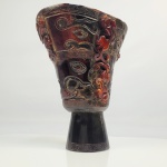 GONGBEI -  PRECIOSA TAÇA DE LIBAÇÃO  ENTALHADA EM CORNO DE RINOCERONTE. ESTA NÃO É UMA TAÇA COMUM DE LIBAÇÃO, É UMA ESCULTURA RITUAL DE PRESTÍGIO, PERCEBA QUE O INTERIOR FOI MUITO POUCO ESCAVADO, FOI PLANEJADA PARA PARA PRESERVAR O  MÁXIMO O MATERIAL CÓRNEO  E PARA  QUE A CONCAVIDADE CONTIVESSE APENAS UMA PEQUENA QUANTIDADE DE LÍQUIDO. MAS CHAMA TAMBÉM A ATENÇÃO O PRIMOR DA DECORAÇÃO. A CONCAVIDADE SUPERIOR É EMOLDURADA POR UMA GREGA/MEANDRO TRADICIONAL  CHAMADO LEIWEN. MESMA DECORAÇÃO NA PARTE INFERIOR DA TAÇA JUNTO A BASE. O CORPO TEM FEITIO DOS VASOS RITUAIS GU ARCAIZANTES. A DECORAÇÃO ENTRETANTO É REFINADA, EMBORA ESTEJAM AI OS ELEMENTOS DE SUA INSPIRAÇÃO BASEADA  NA ORNAMENTAÇÃO DOS BRONZES RITUAIS SHANG E ZHOU (1600 A 256 AC) VEJA AS MÁSCARAS TAOTIE E OS DRAGÕES CHILONG, ELES SÃO DISPOSTOS DE FORMA ELABORADA E NADA PRIMITIVA COMO ESPERARIAMOS EM UMA PEÇA ARCAICA. SOB A BASE UM SELO ZHUANZHU  COM CARACTERES DE ESTILO ARCAICO DESGASTADOD EMOLDURADO POR UM CÍRCULO. O DESGASTE DO SELO ASSIM COMO DA BORDA DA CONCAVIDADE SÃO NATURAIS PERMITINDO CONSTATAR TRATAR-SE DE DESGASTE COMPATÍVEL COM O USO E O TEMPO. INFERIMOS ENTÃO SER ESTA UMA TAÇA DE LIBAÇÃO PARA PEQUENAS OFERENDAS (DEVIDO A CAPACIDADE REDUZIDA DA CONCAVIDADE SUPERIOR) COMO UMA PEQUENA QUANTIDADE DE INCENTO EM PÓ, UMA PÉROLA OU UMA ESFERA DE JADE, UM PERFUME RARO OU OUTRA OFERENDA RITUAL MUITO PEQUENA. MUITO PROVAVELMENTE TRATA-SE DE UMA TAÇA DE ALTAR. CHINA, DINASTIA QING (QIANLONG OU  FINAL DO SEC. XVIII. 15,5 X 14 X 10 CM 515 GNOTA: O chifre de rinoceronte é considerado um dos OITO SÍMBOLOS PRECIOSOS. Era conhecido pelos chinese por seu poder de detectar veneno, o que levou a confecção de recipientes destinados a alimentação e a ingestão de bebidas com esse material. Segundo a tradição uma taça feita de chifre de rinoceronte faria um líquido ou alimento envenenado espumar, borbulhar ou mudar de comportamento ao simples contato. Hoje sabemos que não há evidências científicas que comprovem isso (infelizmente para os rinocerontes esse mito foi desfeito há apenas um século) contudo essa crença foi muito influente entre as elites chinesas especialmente entre as dinastias Ming e Qing. Por isso taças de chifre de rinoceronte eram consideras objetos de grande prestígio. TAÇAS DE LIBAÇÃO: As taças de libação chinesas são recipientes rituais usados para derramar líquidos  como vinho de arroz ou chá  em homenagem aos deuses e antepassados. Elas destacam-se pelo uso de chifre de rinoceronte, formas arcaicas de bronze e detalhes mitológicos. O design frequentemente copiava o estilo dos vasos de sacrifício da antiguidade conhecidos como gng, usados para misturar e verter o vinho em banquetes solenes.  As alças e corpos das taças eram enfeitados com dragões Chilong, fênix e máscaras taotie, representando proteção, boa sorte e poder espiritual.  líquido sagrado era derramado segurando o recipiente com as duas mãos e em direção horizontal (da direita para a esquerda) diante de altares, ou diretamente no chão para honrar os mortos.