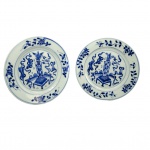 REINADO KANGXI  PAR DE PRATOS (DE UMA SEGUENCIA EM QUE SERÃO APRESENTADOS SEIS DO MESMO CONJUNTO) EM PORCELANA CHINESA DO PERÍDO KANGXI (16621722)  DECORADOS EM ESMALTES AZUIS UNDERGLAZE.  UMA DAS ERAS DE MAIOR PRESTÍGIO E QUALIDADE NA HISTÓRICA DA PORCELANA AZUL E BRANCA DA CHJINA. COM DECORAÇÃO FLUIDA E ELEGANTE TEM NA ABA REMOS CONINUOS E SINUOSOS QUE SE ESTENDEM AO LONGO DE TODA A CIRCUNFERÊNCIA. ESSES RAMOS ALTERNAM ENTRE FOLHAS LANCEOLADAS DETALHADAS E BOTÕES DE FLORES ESTILIZADOS. NA TRADIÇÃO DA PORCLEANA CHINESA ESSES ARRANJOS DE TREPADEIRAS E FLORES NA BORDA NÃO SÃO MERAMENTE ESTÉTICOS, REMETEM A IDEIA DE CONTINUIDADE, LONGEVIDADE E RENOVAÇÃO CONSTANTE. A CALDEIRA É DECORADA EM PADRÃO BOGU QUE SIMBOLIZA VOTOS DE REFINAMENTO E BOA FORTUNA. ESTÃO NA CALDEIRA UM VASO CENTRAL QUE REMETE AS 100 ANTIGUIDADES, POUSADO SOBRE UM SUPORTE QUADRADO CLÁSSICO. O VASO É DECORADO COM ARRANJOS FLORAIS INDICANDO REFINAMENTO ACADÊMICO. FITAS FLUIDAS DITAS RIBBONS ENVOLVEM A MESA E O VASO ESSAS FITAS ESTÃO SEMPRE PRESENTES QUANDO SE APRESENTAM OS OBJETOS PRECIOSOS QUE INTEGRAM AS 100 ANTIGUIDADES. POSTERIORMENTE AOS VASOS ESTÁ UM TABULEIRO COM PADRÃO QUADRICULADO QUE REPRESENTA O JOGO MILENAR WEIGI UM DOS QUATRO TALENTOS ESSENCIAIS EXIGIDOS DE UM ERUDITO CHINÊS TRADICIONAL.  DELIMITANDO A CALDEIRA DA BORDA DUAS MOLDURAS DE LINHAS CONCÊNTRICAS DUPLAS. RARAMENTE SE ENCONTRARÃO DISPONÍVEIS SETS DE PORCELANA KANGXI COMO ESTE COM SEIS PRATOS  DE UM MESMO PADRÃO. CHINA, FINAL DO SEC. XVII OU INICIO DO XVIII. 23 CM DE DIAMETRONOTA:  Há 800 anos Marco Polo, trouxe da China para o ocidente a primeira peça de porcelana, um pequeno jarro verde acinzentado que está até hoje no tesouro da Basílica de São Marco em Veneza. Essa foi a semente da obsessão da Europa pelo Ouro Branco. No crepúsculo da DINASTIA MING, chegou à China em 1698 o Padre Jesuíta François Xavier d'Entrecolles. O declínio Ming sobreveio de uma crise causada pela corrupção, a exploração da classe dominante e desastres naturais durante anos sucessivos. Os rebeldes começaram a tomar o poder em algumas regiões e a dinastia chegou ao seu oficial fim com o suicídio do último imperador, Weizong. O poder passou então a nascente Dinastia Qing, que por 250 anos governou a China e sobre seu domínio a produção da porcelana Companhia das Indias atingiu seu apogeu em beleza e volume. Estima-se que 60 milhões de peças de porcelana foram exportadas para Europa nesse período. O Imperador QIANLONG governou o país por quase todo o sec. XVIII. Pouco antes do inicio desse grande reinado, ainda sob o período KANGSHI chegou a China o Padre DEntrecolles. Veio para salvar almas dos pagãos mas teve a sua própria alma arrebatada pela obsessão da porcelana. O ouro branco, encantou os europeus desde o primeiro leilão fruto da carga apreendida pelos holandeses de dois navios Portuguses. Era tão alto o preço da porcelana da China que um aparelho de jantar custava o equivalente ao valor de um pequeno palácio. Foi então que na Europa começou a busca da fórmula da composição e do processo para fabricação da porcelana. A princípio, julgaram que era feita a partir de conchas e casca de ovos moídos e tentaram reproduzir o efeito com esses matérias. Claro, tudo em vão porque a porcelana nada tinha a ver com esses elementos. O primeiro Imperador da Dinastia Qing foi Kangxi e este deu ordens de esconder, sob pena de morte, o processo de fabricação. O Padre DEntrecolles valeu-se dos chineses convertidos de Jingdezhen para descobrir aos poucos o processo. Um dia finalmente ele descobriu o segredo mais importante para obtenção da porcelana, em uma região remota chamada KAO-LING (COLINA ELEVADA) os chineses extraiam há séculos a argila chamada caulim que era o principal elemento constituinte da louça da China. O resto, as proporções, o modo de fazer, de decorar e a queima ele cuidou em aprender gradativamente. Em 1712 o Padre DEntrecolles escreveu para França relatando suas descobertas e descrevendo em minúcias o processo de fabricação. Dessa forma um segredo milenar foi revelado a Europa ensandecida pela porcelana e sua capacidade de trazer riquezas além de qualquer sonho aos homens. Paralelamente na Europa, Augusto II, chamado O FORTE, aprisionou em seu castelo um jovem aprendiz chamado BOTTEGER, que se gabava de ser alquimista, e o ameaçou de pena de morte se não conseguisse desvendar o processo para a fabricação. Cinco anos BOTTEGER esteve preso realizando experimentos sistemáticos até chegar por seu próprio mérito à fórmula da porcelana. Embora não tenha sido um método muito ortodoxo, funcionou. Surgiu a manufatura de Meissen. Nessa mesma época na China, LANG TINGJI, foi nomeado pelo Imperador KANGXI, supervisor de porcelana nos fornos de Jingdezhen. A intenção do Imperador era a de recriar as famosas porcelanas monocromáticas do período Ming do SEC. XIV. Os chineses tem essa particularidade, um respeitoso culto aos ancestrais e suas conquistas. Edmund de Waal em seu livro O Caminho da Porcelana: A jornada de Uma Obsessão (recomendo muitíssimo) referencia assim essa respeitosa paixão pela memória dos ancestrais: Esse pode ser o ano em que alguém encomenda a fabricação de turíbulos que se parecem muito com os turíbulos feitos há trezentos anos. Esses por sua vez foram feitos para aludir bronzes de 900 anos atrás. Assim a devoção atravessa os séculos e as gerações. A porcelana chinesa antiga ainda traz encantamento por sua beleza, sua coloração branca azulada e a magnífica decoração. Não por acaso, cada peça de porcelana Companhia das Índias que nos chega à mão é tratada com reverência e devoção não apenas por ser fruto do trabalho do oleiro que lhe deu forma e a decorou, mas por ser produto de 5000 anos de uma cultura extraordinária e única. AS CEM ANTIGUIDADES O PRINCIPIO DAS COISAS:As "Cem Antiguidades" (Baigu ou Po-ku) é um famoso tema decorativo da arte chinesa que reúne emblemas de boa sorte, sabedoria e erudição, refletindo os ideais da classe letrada tradicional. O motivo não representa exatamente cem objetos literais, mas sim uma rica coleção de itens associados à cultura, ao estudo e à filosofia na China antiga. Das cem antiguidades se originaram tudo que existe no mundo. Objetos de Estudo: Pincéis, blocos de tinta, papel e pedras de amolar tinta (os quatro tesouros do letrado).Artes e Passatempos: Instrumentos musicais, tabuleiros de xadrez chinês, livros e rolos de pintura ou caligrafia. Rituais e Símbolos: Vasos de bronze arcaicos, queimadores de incenso, cetros ruy de prosperidade e recipientes rituais que homenageiam os antepassados. Esse repertório visual consolidou-se fortemente durante a dinastia Qing (16441911) e era aplicado em porcelanas, pinturas e painéis. Demonstra a busca por virtude, refinamento intelectual e o respeito contínuo aos ancestrais. Cada objeto funciona como um símbolo ou enigma visual que deseja vida longa, paz, felicidade e riqueza para o lar. 