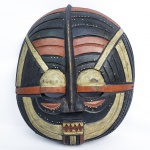 MÁSCARA RITUAL KIFWEBE - POVO LUBA   CONGO  - LINDA MÁSCARA EM MADEIRA DE FEIÇÃO ARREDONDADA. VISUALMENTE MARCANTES, ELAS SÃO FAMOSAS POR SEUS PADRÕES GEOMÉTRICOS DE LINHAS INCISAS E VISUAL ABSTRATO QUE INFLUENCIOU PROFUNDAMENTE O MODERNISMO OCIDENTAL NO INÍCIO DO SÉCULO XXA MÁSCARA DE MADEIRA É APENAS A CABEÇA; O DANÇARINO VESTE UM TRAJE DE FIBRAS VEGETAIS E RÁFIA QUE COBRE TODO O SEU CORPO. AS RANHURAS BRANCAS NA MADEIRA SÃO PREENCHIDAS COM ARGILA BRANCA (KAOLIN), QUE OS POVOS LOCAIS ASSOCIAM AO MUNDO DOS ESPÍRITOS E À PUREZA.OS OLHOS PROJETADOS PARA FORA IMITAM OS OLHOS DE UM CAMALEÃO, SIMBOLIZANDO VIGILÂNCIA E A HABILIDADE DE ENXERGAR TUDO AO REDOR. O VISUAL ABSTRATO E LINEAR DAS MÁSCARAS KIFWEBE CHOCOU E INSPIROU ARTISTAS EUROPEUS COMO PABLO PICASSO, INFLUENCIANDO DIRETAMENTE O CUBISMO. ÁFRICA, INICIO DO SEC. XX. 52 X 44 CMNOTA: Tradicionalmente, as máscaras Luba kifwebe redondas e estriadas são utilizadas em práticas benevolentes para purificar a comunidade dos espíritos malignos dos feiticeiros. As máscaras kifwebe participavam de iniciações e desempenhavam um papel no estabelecimento da ordem na sociedade.