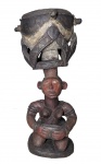 TAMBOR CERIMONIAL CARIÁTIDE A-NDËF  POVO BAGA  GUINÉ - O A-NDËF (TAMBÉM TE-NDËF) É UM TAMBOR EM FORMA DE CARIÁTIDE ENCONTRADO NAS TRADIÇÕES MUSICAIS DO POVO BAGA, UM GRUPO ÉTNICO DO OESTE DA GUINÉ. ESTÁ ASSOCIADO AO A-TËKÄN, A INSTITUIÇÃO BAGA DE SOLIDARIEDADE FEMININA, E É TOCADO EM DIVERSOS EVENTOS IMPORTANTES PARA AS MULHERES. A FORMA DO INSTRUMENTO  ESPECIFICAMENTE, A REPRESENTAÇÃO DE UMA FIGURA FEMININA SUSTENTANDO UM OBJETO GLOBULAR SOBRE A CABEÇA  É COMUM AOS TAMBORES BAGA. TAMBÉM EVOCA OS PAPÉIS DAS MULHERES BAGA NA SOCIEDADE. NÃO APENAS AS MULHERES CARREGAM GRANDES RECIPIENTES DE BARRO PARA ÁGUA OU CESTOS PARA ALIMENTOS, PRINCIPALMENTE ARROZ, SOBRE A CABEÇA, COMO TAMBÉM AS MULHERES SÃO AS PORTADORAS DA SOCIEDADE BAGA EM TODOS OS SENTIDOS DA PALAVRA. , O A-TËKÄN, CUJA COMPOSIÇÃO É TIPICAMENTE EXCLUSIVA DE MÃES, É UMA DAS INSTITUIÇÕES RITUAIS MAIS DURADOURAS DO POVO. AS APRESENTAÇÕES DE A-TËKÄN, QUE CONSISTEM EM UM GRUPO DE PERCUSSIONISTAS E UM CÍRCULO DE DANÇARINAS, ACONTECEM EM CASAMENTOS OU FUNERAIS DE MULHERES ANCIÃS IMPORTANTES, ENTRE OUTROS EVENTOS. A DANÇA É FREQUENTEMENTE ACOMPANHADA POR CANÇÕES COM LETRAS QUE ABORDAM PROBLEMAS UNIVERSAIS DA MATERNIDADE. ESTE A-NDËF É ESCULPIDO EM UMA ÚNICA PEÇA DE MADEIRA. NO TOPO, É CIRCUNDADO POR UMA SERPENTE, QUE FAZ REFERÊNCIA AO ESPÍRITO DA SERPENTE NA SOCIEDADE BAGA E PROVAVELMENTE SIMBOLIZA TAMBÉM A FERTILIDADE. A FIGURA FEMININA QUE SUSTENTA O TAMBOR ESTÁ AJOELHADA EM SINAL DE DEVOÇÃO. GUINÉ, INICIO DO SEC. XX. 69 CM DE ALTURANOTA: Os Baga são o que alguns antropólogos chamam de acéfalos, o que significa que não possuem um estado ou reino histórico. Os Baga migraram para oeste, de sua terra ancestral em Futa Jalon, na atual Guiné central, para a costa oeste da Guiné, onde sua presença foi documentada pela primeira vez no século XVI, a fim de resistir à conversão ao Islã. Uma vez na costa, escreve Lamp, os Baga inventaram ou descobriram, afirmam, uma impressionante variedade tanto de seres espirituais quanto de ideias espirituais, em torno das quais suas tradições culturais estão organizadas. Os espíritos Baga tendem a ser separados por gênero: um espírito masculino, frequentemente assumindo a forma de uma serpente ou pássaro; e um espírito feminino, às vezes assumindo a forma de uma tartaruga marinha. Os tambores Baga também são separados por gênero. O a-ndëf, em particular, é associado ao feminino. Essa divisão de gênero não deve ser rígida, mas sim inclusiva e interconectada por natureza, escreve Lamp. Assim, o a-ndëf pode, em certas ocasiões, ser tocado por um homem. Durante o baile de máscaras de a-Bol, um espírito feminino, por exemplo, os homens se vestem com roupas do sexo oposto e tocam o a-ndëf. O equivalente masculino do a-ndëf, a timba, maior, no entanto, é tocado exclusivamente por homens. Ao longo do século XX, o povo Baga e suas tradições foram violentamente reprimidos. Primeiramente, durante a ocupação colonial francesa, explica Lamp, a demanda por objetos de arte africana na França quase despojou a paisagem cultural Baga de antigas máscaras e esculturas rituais. Poucos anos antes da independência da Guiné, entre 1956 e 1957, missionários muçulmanos Malinke e Susu invadiram aldeias, derrubaram florestas sagradas e torturaram opositores à conversão ao Islã no território Baga, com a bênção do então ditador Sékou Touré. Após a ascensão de Touré ao poder, as práticas religiosas tradicionais foram declaradas ilegais e severamente punidas. 