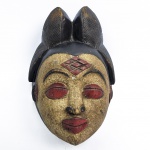 MASCARA PUNO - GABÃO -  TRADICIONALMENTE PATINADAS EM BRANCO COM CAULIM E CINGINDO ELABORABOS PENTEADOS ESSAS MÁSCARAS CARREGAM UM SIGNIFICADO ESPIRITUAL PROFUNDO PARA O POVO PUNO  GABÃO, UMA MÁSCARA PUNU (OU PUNO) É UMAARTEFATO TRIBAL TRADICIONAL DE MADEIRA DO GABÃO, CARACTERIZADA POR UM ROSTO BRANCO SERENO, PENTEADOS ELABORADOS COM TRANÇAS E MARCAS DE ESCARIFICAÇÃO EM FORMA DE DIAMANTE. INICIO DO SEC. XX. 32 CM DE ALTURA NOTA: Quando obras da África Equatorial nesse estilo refinado começaram a entrar na consciência ocidental no início do século XX, representaram um grande enigma para os críticos de arte. Muitos especularam sobre as origens de sua estética exótica e até propuseram uma possível influência asiática, embora a forma de arte fosse, na verdade, originária do sul do Gabão. Essas máscaras eram usadas por virtuosos dançarinos de perna de pau chamados "mukudj", que consistiam em se erguerem de forma impressionante enquanto executavam coreografias complexas e acrobacias estonteantes.O criador de uma máscara de "mukudj" buscava capturar a imagem da mulher mais bela de sua comunidade. A retratada nesse retrato idealizado e estilizado era adornada, à moda clássica do século XIX, com um penteado composto por uma mecha central e duas laterais, além de motivos de cicatrizes na testa e nas têmporas. Caulim, extraído de leitos de rios e associado à cura e a um reino espiritual ancestral, era aplicado na superfície do rosto. Ao utilizar esse material, a artista celebrou a beleza de uma mulher mortal e a transformou em um ser transcendente.