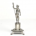 PALITEIRO NETUNO - MAGNÍFICO PALITEIRO DE MESA DE BANQUETE  EM PRATA DE LEI. O DEUS DOS MARES SURGE COROADO, EMPUNHANDO SEU TRIDENTE. SUSTENTADO POR UM PEDESTAL EM FACETAS COM BASE APRESENTANDO ORNAMENTOS FLORAIS ,ASSENTE SOBRE PÉS DE GARRA. MARCAS DE CONTRASTE P COROADO (CIDADE DO PORTO) E PRATEIRO REFERENCIADO POR MOITINHO COMO P362 (PAG 254) ATIVO A PARTIR DA DECADA DE 1830. TRATA-SE DA REPRESENTAÇÃO DO DEUS NETUNO, REI DOS MARES. ESSE PALITEIRO FAZ PARTE DA SÉRIE SURGIDA NO INÍCIO DO SEC. XIX COM PERSONAGENS MITOLÓGICOS E SÃO EXTREMAMENTE COLECIONÁVEIS NO BRASIL E EM PORTUGAL. PORTUGAL, SEC. XIX, 18 CM DE ALTURA.NOTA: A história dos paliteiros, como objetos de coleção e decoração, está ligada à evolução dos hábitos sociais e à apreciação de objetos antigos e requintados. Os palitos de dente surgiram como objetos funcionais, utilizados para higiene bucal após as refeições. Inicialmente, eram simples e feitos de materiais como madeira ou osso. Com o passar do tempo, os palitos evoluíram para objetos mais elaborados, com designs variados, feitos de materiais como prata, ouro e outros metais preciosos. Eram objetos pessoais que usados tanto na residência de seu possuidor quanto levados a banquetes ou refeições fora de sua casa quanto mais ostensivos ou preciosos mais indicavam a riqueza e importância social de seu possuidor. Com o tempo os palitos passaram a ser apresentados em paliteiros levados a mesa para servir a todos os convivas. Evoluíram para objetos mais elaborados, com designs variados, feitos de materiais como prata, porcelana e outros metais preciosos. No Brasil por herança de Portugal os paliteiros assumiam formas decorativas e elaboradas para compor com elegância as mesas. Sendo geralmente confeccionados em prata de lei. Esses paliteiros adornados por esculturas, flores, deuses, pássaros continham orifícios onde os palitos de marfim ou espinhos de laranjeira e limoeiro eram inseridos para o uso. Embora paliteiros existissem em outros locais, nenhum lugar do mundo teve tanta paixão por colecionar e fabricar paliteiros figurativos em prata quanto Portugal e o Brasil. Tornou-se uma especialidade artística da ourivesaria do Porto e de Lisboa. Historiadores de arte apontam que essa profusão de modelos detalhados (com figuras humanas, deuses e animais) é um fenômeno cultural quase exclusivo do mercado luso-brasileiro. A figura de Netuno (Rei dos Mares) pertencia a séries de personagens mitológicos criadas pelos ourives que frequentemente faziam pares. Era muito comum que as famílias ricas comprassem dois paliteiros coordenados para equilibrar a decoração simétrica das grandes mesas: um representando Netuno e outro representando sua esposa, a deusa Anfitrite (Rainha dos Mares)Modelos similares aos existentes no acervo do Museu Imperial eram conhecidos desde o final do século XVIII em Portugal, chegando ao Brasil por influência, e tendo seu auge no século XIX. Os prateiros europeus produziam paliteiros com formas diversas e elaboradas. Personagens históricos, como Vasco da Gama e Napoleão, animais, como pavões e pássaros, frutas como romãs e uvas e flores em ramos e buquês eram frequentes. No Brasil, alguns temas sofreram influência nacional, frutas como abacaxis e cajus, personagens como figuras representando indígenas estilizados, como este exemplar do acervo Museu Imperial, além de elementos africanos, foram representados nos paliteiros utilizados aqui, produzidos principalmente no Rio de Janeiro e Bahia.