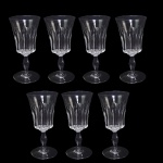 BACCARAT POLIGNAC   COM SELO DA MANUFATURA  .ORIGINALMENTE ENCOMENDA DO GOVERNO FRANCÊS (PRESIDENTE RENÉ COTY) PARA O BANQUETE OFICIAL OFERECIDO EM HOMENAGEM A RAINHA ELIZABETH II NA GALERIA DOS ESPLEHOS DO PALÁCIO DE VERSALHES EM 9 DE ABRIL DE 1957. RÉGIO CONJUNTO COM SETE TAÇAS PARA VINHO TINTO EM CRISTAL DO MODELO POLIGNAC DA BACCARAT. APRESENTA LAPIDAÇÕES VERTICAIS ESPESSAS E PROFUNDAS (ORGUE BEVEL CUTS) QUE SAEM DA HASTE E SOBEM PELO BOJO. O DETALHAMENTO GEOMÉTRICO CRIA UM VISUAL ROBUSTO QUE SIMULA UM CÁLICE MODERNO, CONTRASTANDO COM A SUAVIDADE DA BORDA SUPERIOR LISA. FOI BATIZADO EM HOMENAGEM À DUQUESA DE POLIGNAC, FIGURA HISTÓRICA CONHECIDA POR SEU GOSTO REFINADO E PROXIMIDADE COM A RAINHA MARIA ANTONIETA. FRANÇA, DEC. 1950. 15 CM DE ALTURA.NOTA: O modelo foi criado exclusivamente para servir a Rainha Elizabeth II e o Príncipe Philip em sua visita oficial à França em 1957. Ele decorou a mesa do banquete na Galeria dos Espelhos no Palácio de Versalhes. O presidente francês René Coty encomendou o design para impressionar a monarca com a modernidade do cristal francês. Seus cortes verticais profundos funcionam como prismas que refletem a luz das velas, criando um brilho único na mesa. Cada taça exigia o trabalho de vários artesãos altamente qualificados, conhecidos como Meilleurs Ouvriers de France.do: Devido à lapidação profunda, as taças são notavelmente mais pesadas que os modelos tradicionais. O nome celebra a Duquesa de Polignac, que foi a amiga mais íntima e favorita da rainha Maria Antonieta. As peças produzidas antes de 1936 não tinham logotipo gravado, mas como o Polignac nasceu nos anos 1950, todas as peças originais trazem a marca circular jateada da Baccarat na base.