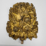 EXUBERANTE PALMA LITÚRGICA EM MADEIRA DOURADA PROFUSAMENTE ENTALHADA COM FOLHAGENS E LINDAS FLORES. IMPRESSIONANTE QUALIDADE ESCULTÓRICA! FINAL DO SEC. XVIII. 50 X 37 CMNOTA: As palmas litúrgicas são elementos fascinantes da arte sacra e da história da Igreja Católica. Embora hoje sejam vistas principalmente como peças de antiguidade e colecionismo, elas carregam séculos de simbolismo, tradição e engenharia artística. No passado, manter flores e palmas naturais frescas nos altares das igrejas era difícil e caro, especialmente no inverno europeu ou em regiões isoladas. As palmas de metal foram criadas como uma solução permanente e luxuosa para garantir que o altar estivesse sempre decorado com a dignidade exigida pela liturgia. Na iconografia cristã, a palma não é apenas um elemento vegetal. Ela é o símbolo máximo da vitória, do triunfo e do martírio. Na Igreja, representa a vitória dos santos e mártires sobre o pecado e a morte (como a recepção de Jesus no Domingo de Ramos). Ter palmas de metal no altar reforçava visualmente essa "vitória celestial".  As palmas litúrgicas eram projetadas especificamente para o ambiente das igrejas antigas, iluminadas por velas. Elas costumam ser planas na parte traseira e ricamente trabalhadas na frente. Isso ocorria porque ninguém as veria por trás; elas ficavam encostadas no retábulo do altar. O acabamento em prata ou outo servia para refletir a luz das velas, criando um efeito luminoso e celestial que ampliava a sensação de magnitude do presbitério.