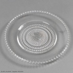 RENNE LALIQUE  NIPPON  COM MARCAS DA MANUFATURA.  PRATO DE SERVIÇO EM CRISTAL DA MNAUFATURA DE RENNE LALIQUE. DECORAÇÃO EM RELEVO COM FILEIRAS CONCÊNTRICAS DE PEQUENAS ESFERAS (PÉROLAS OU "BEADS"). ESSE MODELO FAZ PARTE DE UMA LINHA COMPLETA DE MESA CHAMADA NIPPON, QUE INCLUI TAÇAS DE VINHO, COPOS, JARROS E TIGELAS, ALTAMENTE COLECIONÁVEIS DEVIDO AO EQUILÍBRIO PERFEITO ENTRE A FUNCIONALIDADE E O REFINAMENTO GEOMÉTRICO DO DESIGN ART DÉCO. LISTADO NO CATÁLOGO RAISONNÉ DE FÉLIX MARCILHAC SOB OS MODELOS DE NUMERAÇÃO TÉCNICA VARIANTES (COMO O MARCILHAC 3037 OU 3040, DEPENDENDO DO DIÂMETRO) CATALOGUE RAISONNÉ DE L'OEUVRE DE VERRE DE R.LALIQUE, ÉD. DE L'AMATEUR PARIS, 1994, P. 721. 24 CM