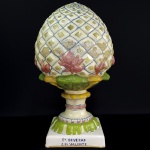 DEVEZAS  BELA PINHA DE FAIANÇA PORTUGUESA  COM FARTA POLICROMIA. PRESENÇA DA INSCRITA APÓCRIFA NA BASE: FÁBRICA DE DEVEZAS   J P VALENTE PORTO  -PORTUGAL, INICIO DO SEC. XX .48 CM DE ALTURA .  NOTA : A Fábrica de Cerâmica das Devesas localiza-se perto da Estação Ferroviária das Devesas, na cidade e concelho de Vila Nova de Gaia, distrito do Porto, em Portugal. Foi fundada em meados da década de 1860 e, durante décadas, foi gerida por uma sociedade constituída por António Almeida da Costa (canteiro ornatista), José Joaquim Teixeira Lopes (estatuário e ceramista) e Feliciano Rodrigues da Rocha (canteiro ornatista). Terá sido a mais importante produtora de artefatos cerâmicos para aplicação na Arquitetura no país. Até 1915, ano da morte de António Almeida da Costa, a fábrica dominou o espectro da produção de azulejaria de fachada, de estatuária e outra ornamentação cerâmica para platibandas e jardins. Nas oficinas de Vila Nova de Gaia ou do Porto - onde ainda hoje existe o edifício da fábrica, na Rua José Falcão - produziram-se ainda artefatos em ferro fundidos e em bronze, maquinaria, cantarias de mármore, túmulos, ornatos para tetos em estuque, e outros. A fábrica dispunha ainda de uma sucursal junto à Estação Ferroviária da Pampilhosa do Botão, onde se produziam materiais de construção. Foi premiada em várias exposições nacionais e internacionais, em finais do século XIX e inícios do século XX. Depois da morte de António Almeida Costa, em 1915, e de José Joaquim Teixeira Lopes, em 1918, a fábrica das Devesas entra num longo processo de declínio, abdicando da produção de obras de arte e passando a dedicar-se essencialmente ao fabrico de materiais para a construção civil. 