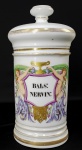 POTE DE FARMÁCIA - MAGNIFICO  POTE DE FARMÁCIA EM PORCELANA ARTISTICAMANETE DECORADO. BASE E TAMPA DECORADAS COM RICOS BARRADOS EM OURO. INTEGRA UM CONJUNTO DE SETE POTES QUE ESTA SENDO VENDIDO EM SEQUENCIA. TODOS ORIUNDOS  DE UMA MESMA FARMACIA. O CORPO TEM EXUBERANTE ESCUDO POLICROMADO ALADO POR NINFAS  ALEGÓRICAS SEGURANDO GUIRLANDAS E UM VASO QUE EMOLDURAM UMA TAÇA DE HÍGIA. A BASE DO ESCUDO TEM REPRESENTAÇÃO DE UMA CABEÇA DE FELINO EM OURO. EM RESERVA APRESENTA O NOME DA SUBSTANCIA QUE CONTINHA SENDO BALS: NERVIN" ESTAMPADA NA CARTELA DO POTE DE FARMÁCIA É UMA ABREVIAÇÃO FARMACÊUTICA EM LATIM PARA  O BALSAMO NERVINO (BALSAMUM NERVINUM) UMA PREPARAÇÃO FARMACÊUTICA CLÁSSICA DAS ANTIGAS BOTICAS, UTILIZADA TOPICAMENTE PARA O ALÍVIO DE DORES NEVRÁLGICAS, REUMÁTICAS, DORES MUSCULARES E INFLAMAÇÕES NAS ARTICULAÇÕES. ERA FORMULADO TRADICIONALMENTE À BASE DE ÓLEOS ESSENCIAIS (COMO ALECRIM, LAVANDA E CRAVO), CÂNFORA, BÁLSAMOS NATURAIS E GORDURA ANIMAL ANIMAL PARA APLICAÇÃO EM FRICÇÕES. MARCAS DO FABRICANTE. FRANÇA. SEC. XIX. 28 CM DE ALTURANOTA: Os potes de farmácia em porcelana com inscrições em latim eram elementos centrais na organização das boticas dos séculos XVIII e XIX. Além da função prática de armazenar medicamentos e unguentos ao abrigo da luz e contaminação, eram símbolos de prestígio, erudição e higiene do boticário.A prática da farmácia nos séculos XVIII e XIX viveu uma transição fascinante: o abandono gradual da alquimia medieval e a consolidação da química moderna e da farmacologia. Durante esse período, as boticas eram mistos de laboratórios artesanais, consultórios e verdadeiros templos da arte decorativa. A Teoria dos Humores e o Galenismo: Até meados do século XIX, a medicina ainda era fortemente influenciada pela teoria dos quatro humores (sangue, fleugma, bile amarela e bile negra). Acreditava-se que as doenças surgiam do desequilíbrio desses fluidos, e os medicamentos serviam para induzir purgas, suores ou vômitos para restabelecer a harmonia corporal.  A Mítica Triaga Magna (Theriac): Um dos remédios mais famosos e caros das boticas era a Triaga, uma fórmula herdada da Antiguidade Greco-Romana que continha de 60 a mais de 100 ingredientes  incluindo carne de víbora seca, ópio, resinas preciosas e metais. O processo de manipulação era público, solene e levava meses de maturação para garantir a "eficácia" contra envenenamentos e pestes.  A Invenção dos Alcaloides no Século XIX: Foi no início do século XIX que a farmácia passou por sua maior revolução científica. Em 1806, o boticário alemão Friedrich Sertürner isolou a morfina a partir do ópio. Pouco depois, foram isoladas a quinina (usada contra a malária), a estricnina e a cafeína, dando origem aos remédios concentrados e dosados. Sanguessugas como Item de Estoque Obligatório: As sangrias eram uma das práticas terapêuticas mais comuns. As boticas mantinham vasos especiais de cerâmica perfurados com água para armazenar milhares de sanguessugas (Hirudo medicinalis), comercializadas para aliviar desde febre até hipertensão. Potes de Botica (Albarelli e Cerâmicas Decorativas): A organização visual das farmácias era questão de prestígio social. Os remédios, bálsamos, elixires e pós ficavam expostos em potes de porcelana ou faiança decorados com ouro, inscrições em latim e elementos mitológicos/alegóricos. A beleza da botica transmitia confiança, higiene e autoridade ao paciente. Gorduras Animais exóticas e Matérias-Primas Curiosas: A manipulação de pomadas e unguentos (como o Bálsamo Nervino) frequentemente utilizava gordura de urso, banha de porco purificada ou cera de abelha como base carreadora para absorção dos óleos essenciais e princípios ativos. A Transição do Latim para as Línguas Vernáculas: O latim era a língua universal das farmacopeias e das inscrições dos potes para garantir uniformidade entre países e manter um certo tom de mistério e autoridade sobre as receitas. Apenas ao longo do século XIX as farmacopeias nacionais passaram a oficializar os nomes dos medicamentos na língua local.