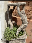 Antigo e diferente vaso em cimento, escultura de dois homens carregando o vaso, mede 85 x 35 x 35 cm.
