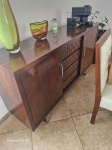 Aparador buffet de alta qualidade com forte inspiração no estilo Art Déco e design modernista. A peça é executada em madeira maciça e revestida com lâmina de madeira nobre de tom  - a agendar a retirada na casa do cliente escuro, apresentando um sofisticado acabamento em verniz de alto brilho. Mede : 170 x 88 m  com 2 portas e 3 gavetas.