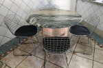 Conjunto de  jantar composto por uma mesa redonda com tampo em mármore maciço, apresentando veios naturais  e acabamento polido , sustentada por uma robusta base   - a agendar a retirada na casa do cliente cônica central também revestida de pedra. Acompanha 4 cadeiras de design clássico inspiradas no modelo Bertoia, confeccionadas em estrutura aramada de aço cromado, todas equipadas com almofadas de assento removíveis na cor preta. Posuem desgaste em algum pontos ( oxidações ) . Mede: 110 cm diametro .Vendida no estado