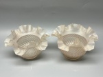 Par de cúpulas em vidro satinê translúcido, com leve tonalidade rosada, decoração em relevo canelado e geométrico pontilhado, e borda ondulada plissada, medidas 9x5,5x14 cm cada. Apresentam marcas do tempo, uso e bicados.