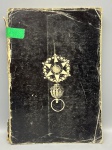 Livro de Referência: "Antiguidades Brasileiras"  Paulo Affonso de CarvalhoObra fundamental para pesquisadores, leiloeiros e colecionadores, escrita por Paulo Affonso de Carvalho. O livro dedica-se ao estudo minucioso de porcelanas antigas de uso real e de alta aristocracia no Brasil, abordando coleções emblemáticas como as da antiga Fazenda Imperial de Santa Cruz e de personalidades como o Conde da Ribeira Grande. O conteúdo detalha características técnicas, simbologias e origens históricas de diversos "serviços" de porcelana, tais como o "Serviço dos Pastores", "Serviço das Corças", "Serviço dos Correios", "Serviço das Rosas", além dos serviços "Vista Grande" e "Vista Pequena". Exemplar com capa ilustrada com representação de insígnia histórica, apresentando desgaste natural do tempo na encadernação.
