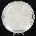METAL PRATEADO, uma (1) antiga salva com fundo em baixo relevo representando parras e laçarotes, borda burilada em elementos vegetalistas, pés perolados com terminações em volutas, marca minúscula não identificada, medindo 29,5 cm diâmetro, sinais de uso, vide foto.