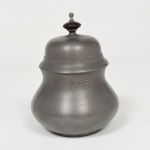 PEWTER, um (1) açucareiro com tampa, pega em madeira torneada, padrão Inglês Georgiano, marca JOHN SOMERS (em 1956 o oficial inglês, nascido em Birmingham, John Somers, radicou-se no Brasil e começou a trabalhar como antiquário no Largo do Boticário, RJ; paralelamente abriu uma oficina de restauro e reproduções de itens antigos em São João Del Rei, MG; em 1968 abriu a empresa John Somers Ltda em São João Del Rei para produzir objetos em estanho e cópias de mobiliário inglês; em 1994 vendeu a empresa que ainda se encontra em funcionamento), medindo 12,5 cm altura, sinais de uso, vide foto.