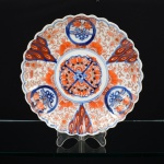 PORCELANA ORIENTAL, um (1) antigo prato decorativo, pintado a mão em policromia no padrão IMARI com elementos vegetalistas, borda recortada, medindo 23 cm diâmetro, vide foto.
