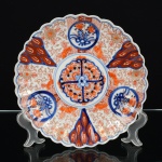 PORCELANA ORIENTAL, um (1) antigo prato decorativo, pintado a mão em policromia no padrão IMARI com elementos vegetalistas, borda recortada, medindo 23 cm diâmetro, vide foto.