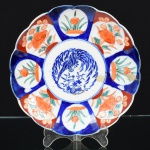PORCELANA ORIENTAL, um (1) antigo prato decorativo, pintado a mão em policromia no padrão IMARI com elementos vegetalistas e ave fênix ao centro, borda recortada, possui trinca acentuada na borda em direção ao centro do prato, medindo 21 cm diâmetro, vide foto.