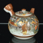 PORCELANA JAPONESA, um (1) bule de chá, padrão Satsuma, ornamentação policromada com guerreiros e elementos vegetalistas, arremates a ouro, selo vermelho em caracteres, medindo 11 cm diâmetro mais a alça e o bico e 11,5 cm altura, vide foto.