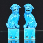 PORCELANA, par (2) esculturas representando casal de cães de fó  (sagrados animais fantásticos com aparência de leão que guardam os Templos Budistas, termo originário da China, pois fó significa Buda, geralmente representado como casal onde o macho brinca com uma bola que significa a terra e a fêmea protege a cria), na tonalidade azul turquesa, medindo 11,5 cm de altura.