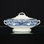 FAIANÇA INGLESA, uma (1) terrina oval com tampa, modelo FLORENCE, marca HOLLINSHEAD & KIRKHAM (fundada no ano de 1870, por John William Hollinshead; Samuel Hollinshead e Samuel Kirkham, em Burslem; em 1876 assumiram a Woodland Pottery e se transferiram para Tunstall; em 1878 Samuel Hollinshead deixa a sociedade; em 1890 a Unicorn Pottery em Tunstall foi reconstruída e as atividades foram transferidas para lá; em 1891 os negócios passaram a ser conduzidos por John Kirkham e George Frederick Helé, mas mantiveram a razão social; em 1902 Helé deixou a sociedade; em 1915 Clarice Cliff trabalhou como litógrafa na fábrica; em 1956 foi vendida para Johnson Bros), ornamentação floral na tonalidade azul e branca, medindo 31 cm de comprimento até as alças, sinais de uso, vide foto.