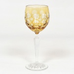 CRISTAL OVERLAY, uma (1) taça de pé alto para vinho, translúcida, bojo amarelo sobre incolor, lapidado em estrelas e esferas, fuste com facetado hexagonal e base em bolacha com fundo estrelado, ambos incolores, medindo 19 cm altura, vide foto.