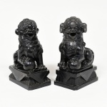 ESCULTURAS, par (2) entalhadas em ônix negro, representando casal de cães de fó (sagrados animais fantásticos com aparência de leão que guardam os Templos Budistas, termo originário da China, pois fó significa Buda, geralmente representado como casal onde o macho brinca com uma bola que significa a terra e a fêmea protege a cria), um deles quebrado e colado na base, apresentam pequenos defeitos, medindo 22 cm altura, vide foto.