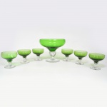 MURANO, conjunto para sobremesa com sete (7) itens translúcidos: 1 saladeira de pé alto com bojo na tonalidade verde, fuste com canelado espiralada e base em bolacha, ambos incolores, medindo 21,5 cm diâmetro e 18 cm altura, acompanham 6 taças na mesma padronização, medindo 10 cm de diâmetro e altura, íntegras, vide foto.